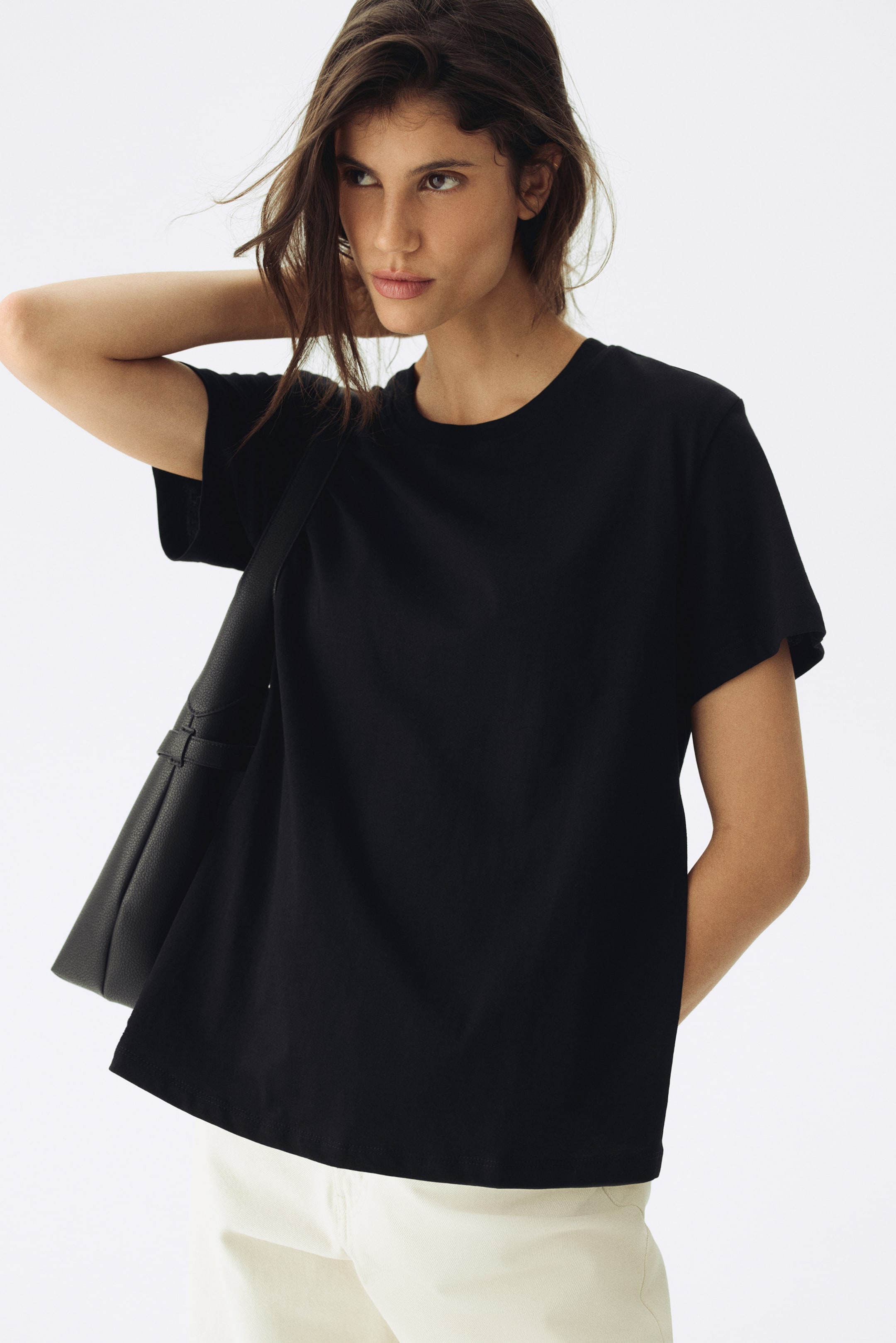 View larger image: A black t-shirt is featuring a crew neck, short sleeves, and a straight hem. It is presenting a relaxed fit in smooth fabric, angled slightly to the right.