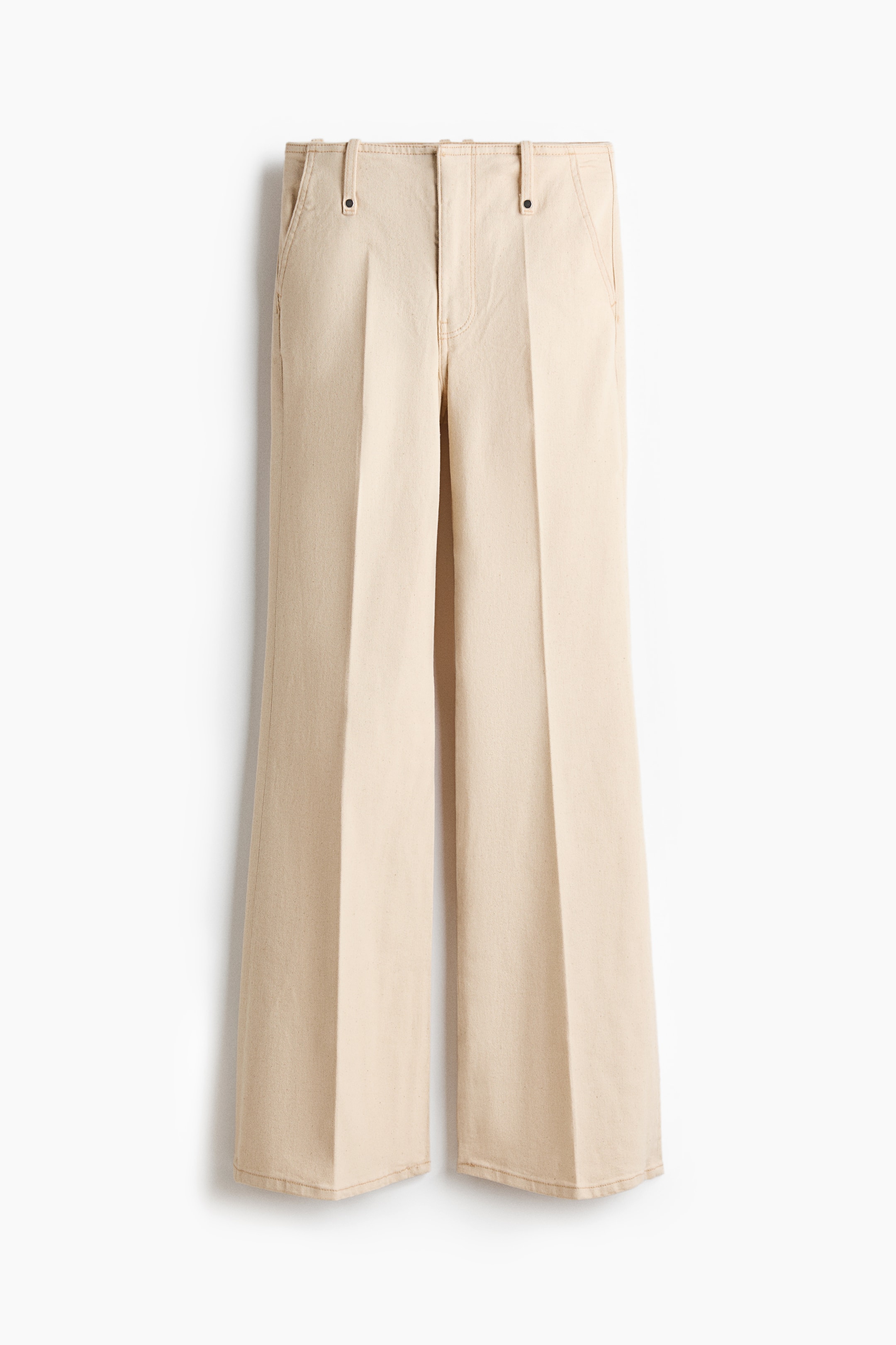 Ver imagen más grande: Pantalones, FRENTE. Los pantalones de pierna ancha en beige claro presentan trabillas para cinturón, bolsillos delanteros inclinados con pequeños remaches de metal y pliegues distintivos que recorren la parte delantera de cada pierna.