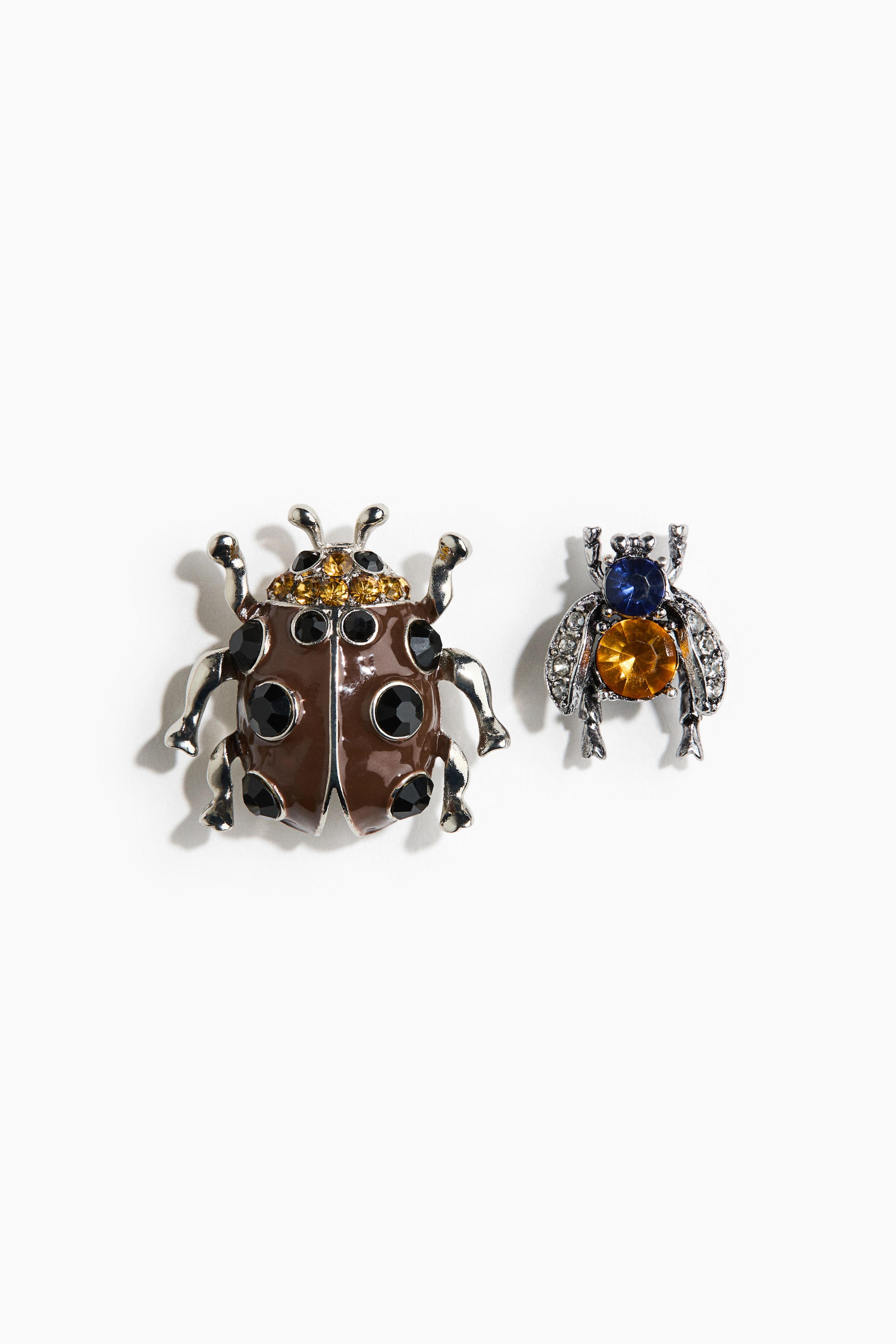 View larger image: Two insect-shaped brooches are depicted in a frontal view. The larger brooch showcases a ladybird design in brown enamel, embellished with black and gold faceted rhinestones and silver-toned legs. Meanwhile, the smaller brooch features a silver-toned bee design, adorned with a blue faceted rhinestone on its head, an orange faceted rhinestone body, and clear rhinestone wings.
