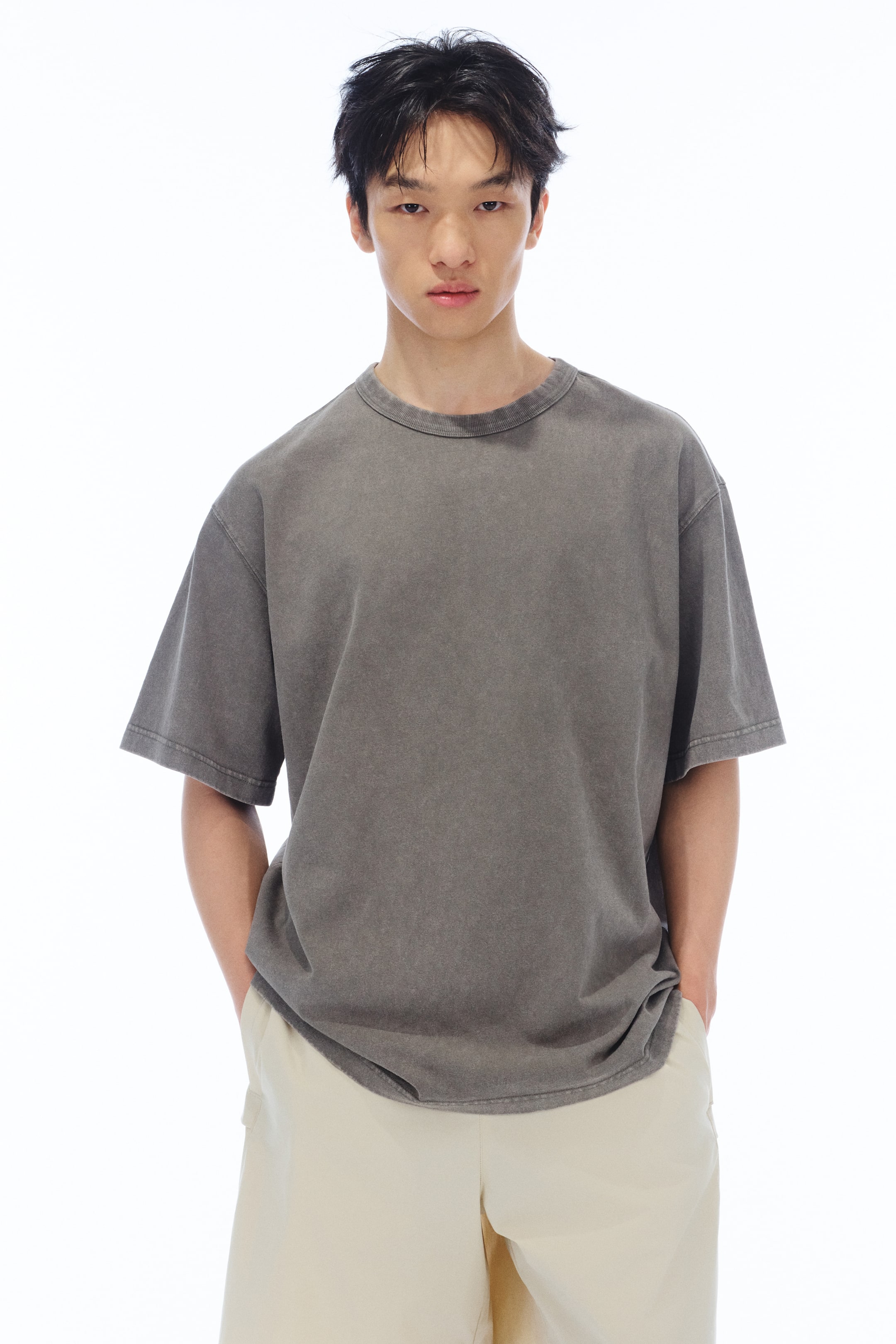 View larger image: The model is wearing a dark grey, faded crew neck t-shirt with short sleeves, showcasing a relaxed fit.
