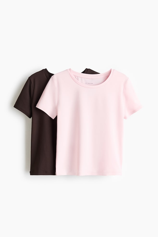 A 2-pack of sports tops is displaying a light pink short-sleeved crew neck top facing front, with "DRYMOVE" visible on its interior neck label, and a dark brown short-sleeved crew neck top partially visible behind it. - 1