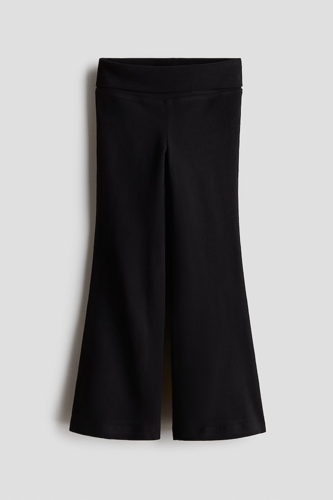 A pair of black flared trousers is facing front, featuring a wide, flat waistband and a fit that gradually widens into a dramatic flared leg. The smooth, stretch-knit fabric is hanging straight to showcase the clean-finished hems and wide-leg silhouette. - 1