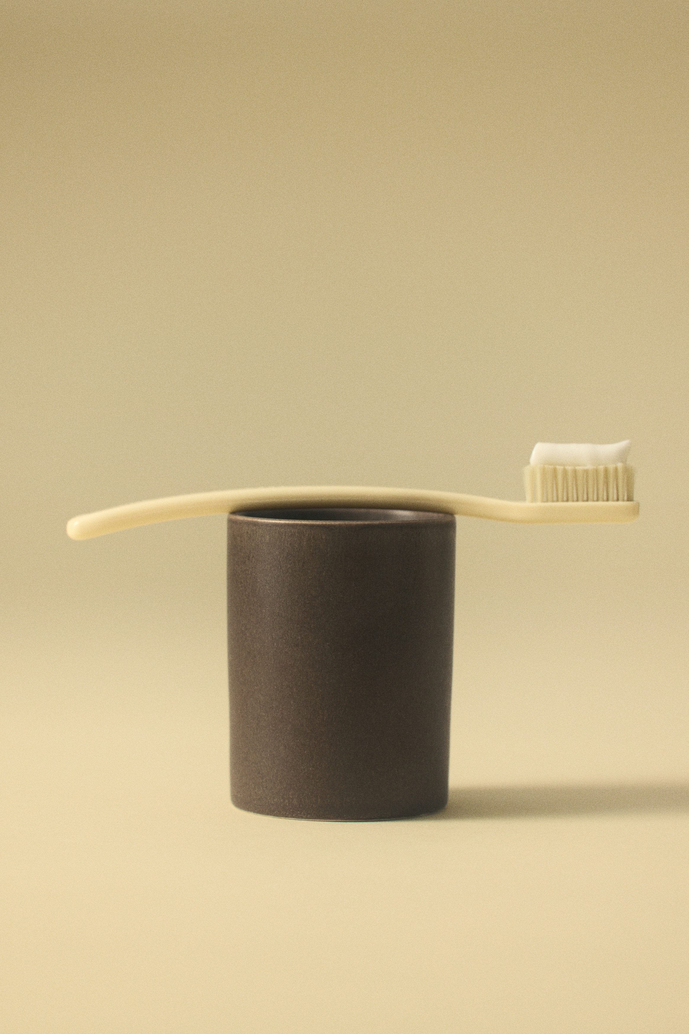 Una taza de gres cilíndrica de color marrón oscuro se presenta desde el frente, con un acabado esmaltado mate sutilmente texturizado y un diseño limpio de lados rectos.