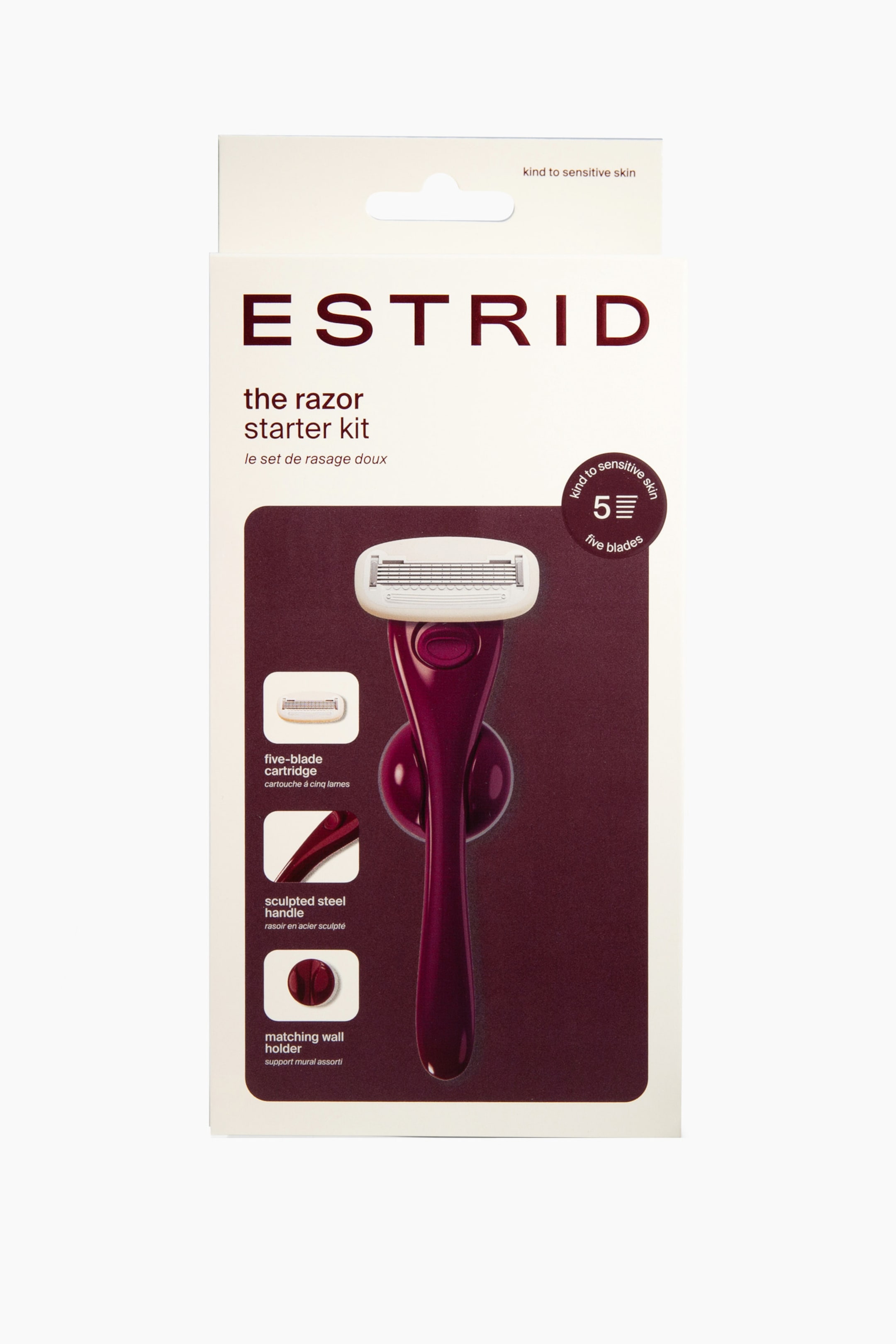 Se større billede: Emballagen til Estrid-razor startsættet står oprejst og viser en cremefarvet æske med mørk bordeaux branding og grafik. Forsiden af æsken har et stort billede af den mørk bordeaux razor med et hvidt fembladet patronhoved monteret på en matchende vægholder, sammen med tre små indsatse fotos, der fremhæver dens vigtigste funktioner.