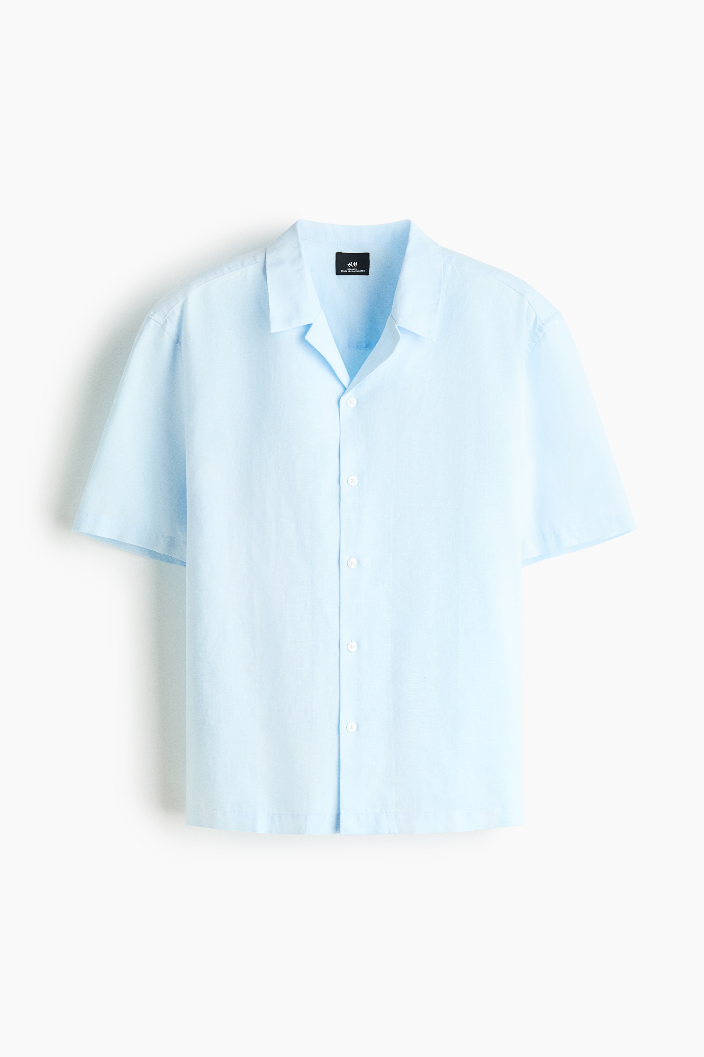 Má»t chiếc áo sÆ¡ mi tay ngắn mà u xanh nhạt, là m từ vải dá»t cotton và linen có bá» mặt ná»i, ÄÆ°á»£c ngưá»i mẫu mặc má» cúc. Ão có phom dáng thoải mái, cá» resort và lai áo cắt thẳng, ÄÆ°á»£c phá»i bên ngoà i áo hai dây trắng gân cùng quần jeans xanh.