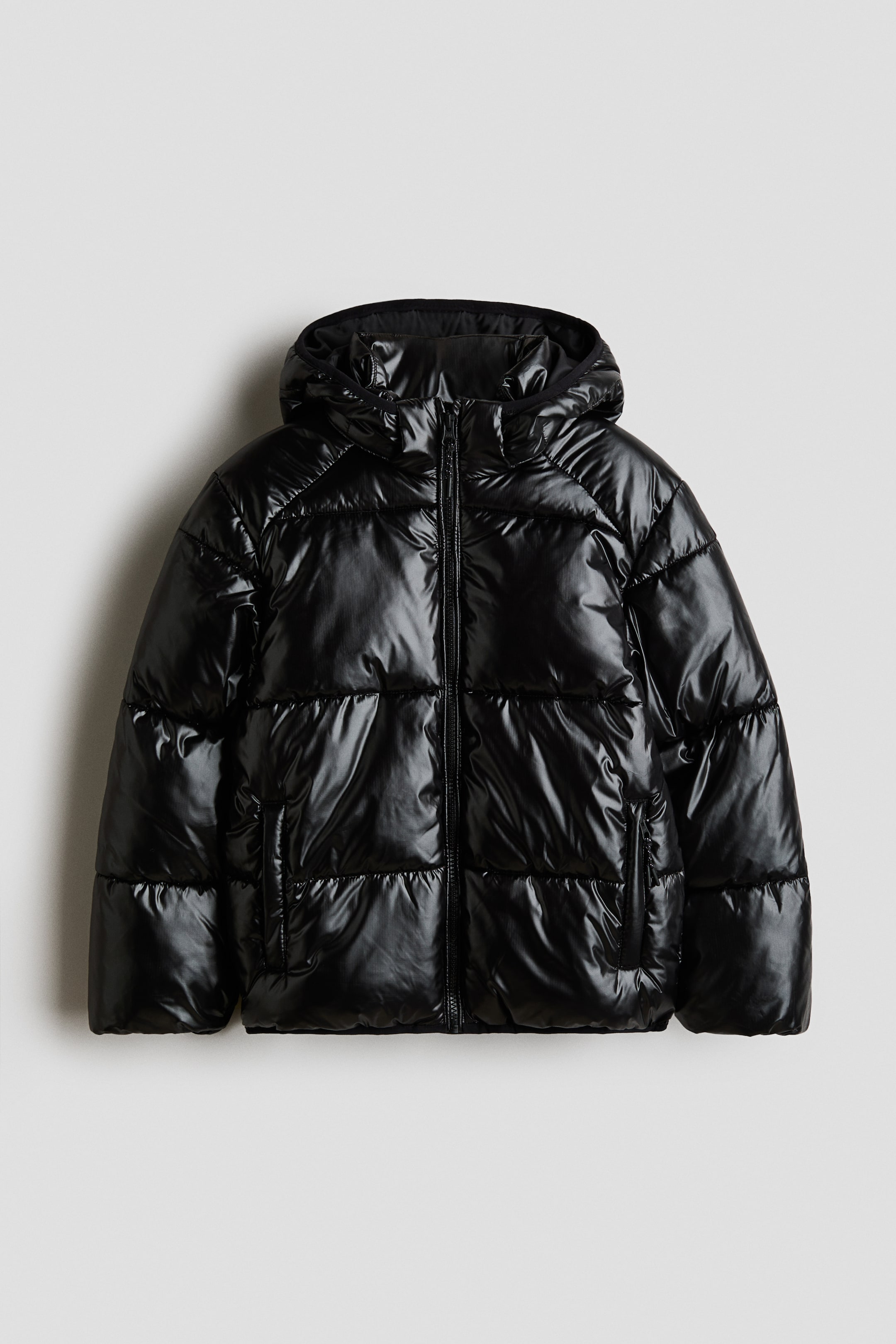 View larger image: A front-facing black padded jacket featuring a glossy quilted weave. It has a full-length front zipper closure, a stand collar, a hood, and welt front pockets with concealed zippers.