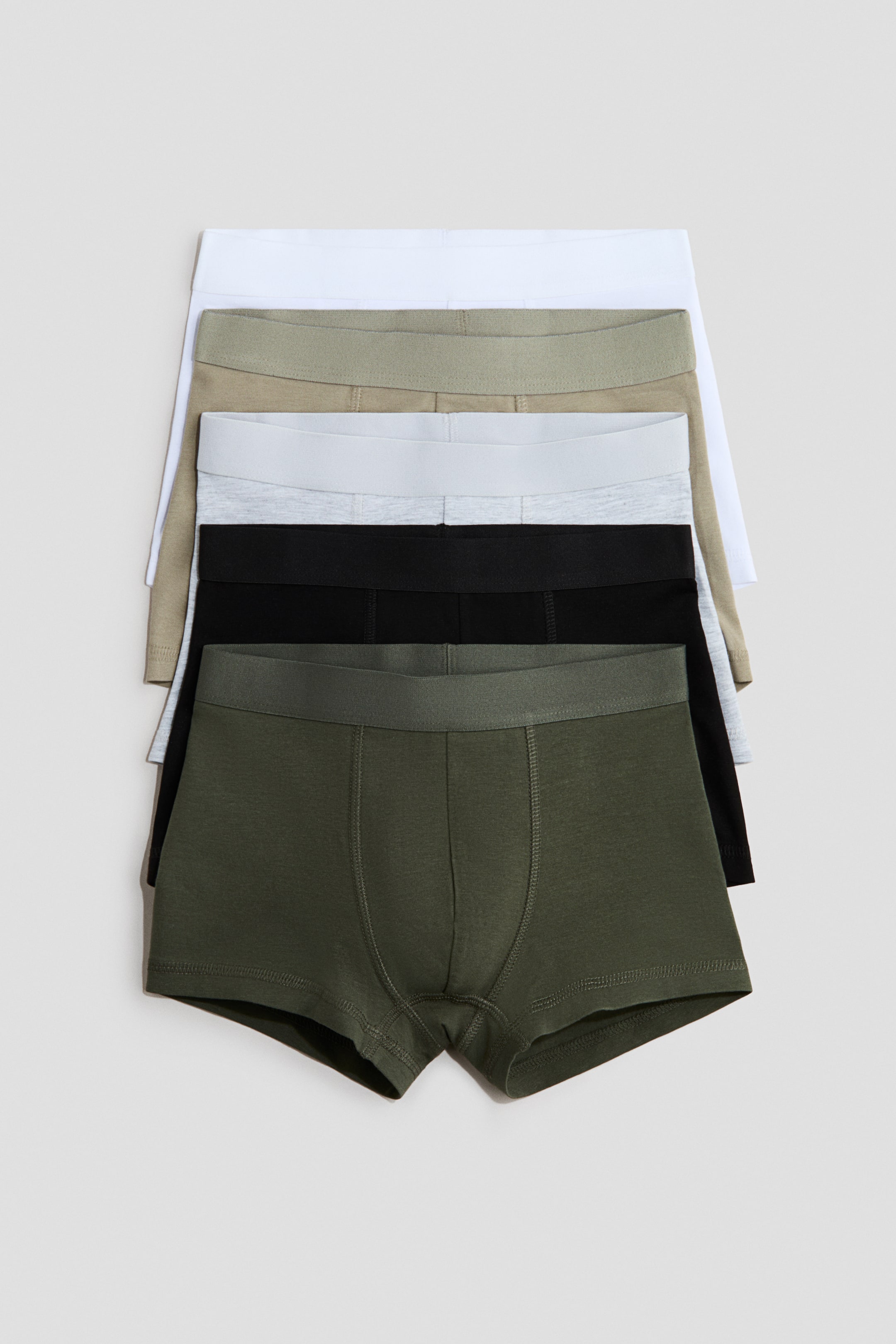 View larger image: Five pairs of cotton jersey trunks are stacked, with the bottom pair facing forward. The trunks feature short legs, an elastic waistband, and a lined front, available in olive green, black, light gray, beige, and white.