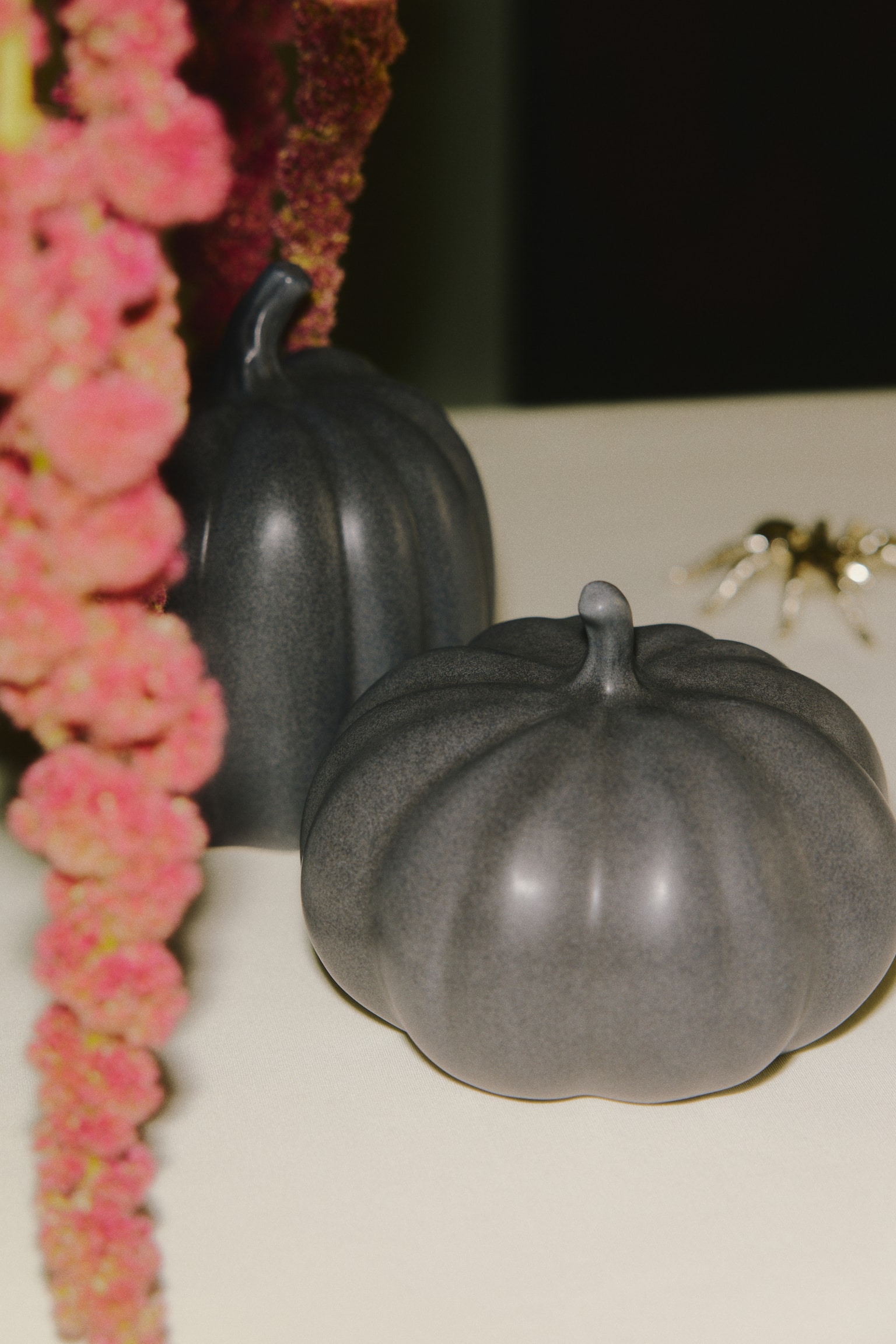 Une décoration en grès en forme de citrouille présente une surface gris foncé mouchetée avec des côtes verticales distinctes et une tige courte et incurvée. - 1