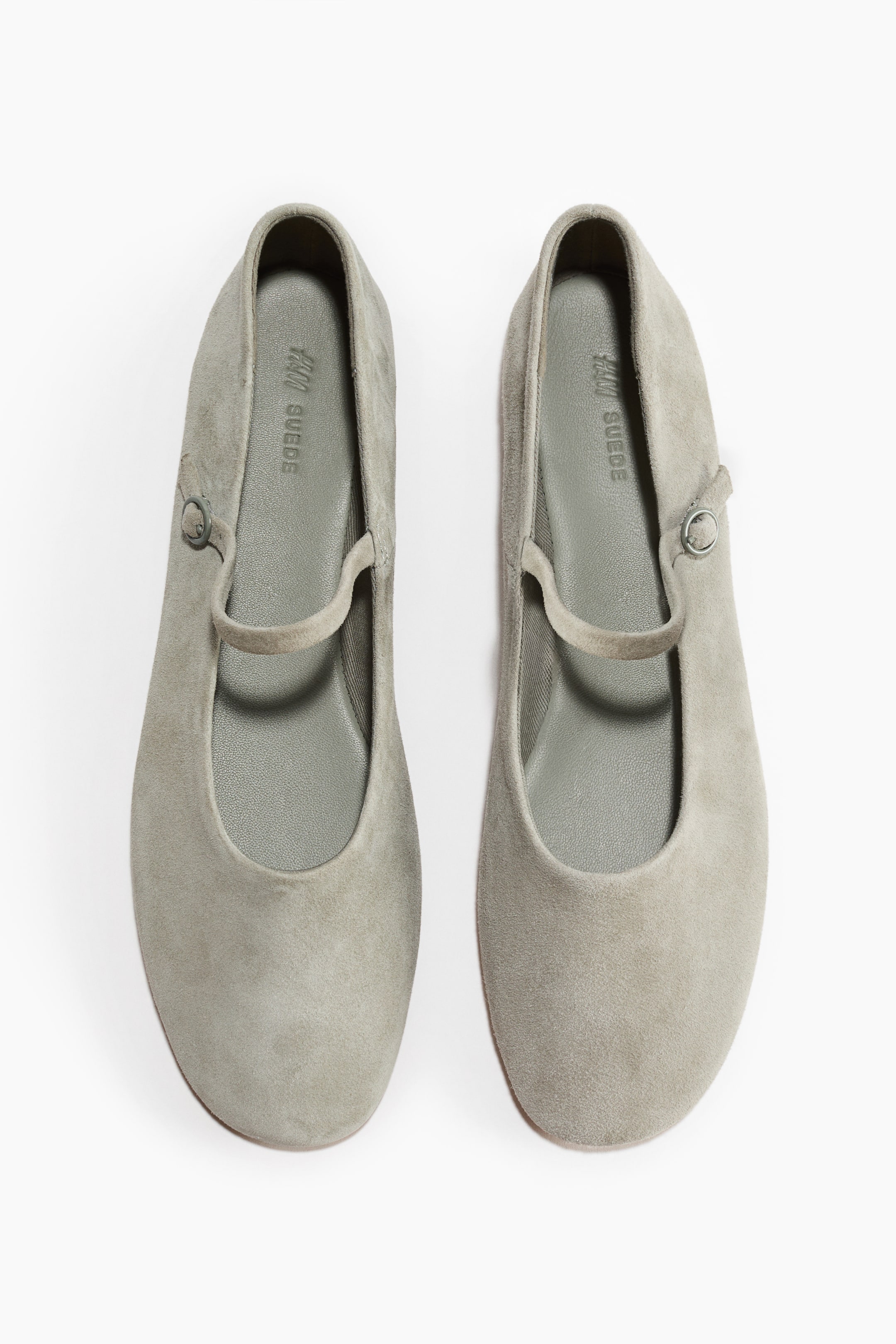 Büyük resmi görüntüle: Önden gösterilen Mary Jane tarzı bir çift bale babet, yumuşak süetten üretilmiş olup yuvarlak burunlara sahiptir. Her babetin üst kısmından metal tokalı ayarlanabilir bir ayak bandı geçmektedir.