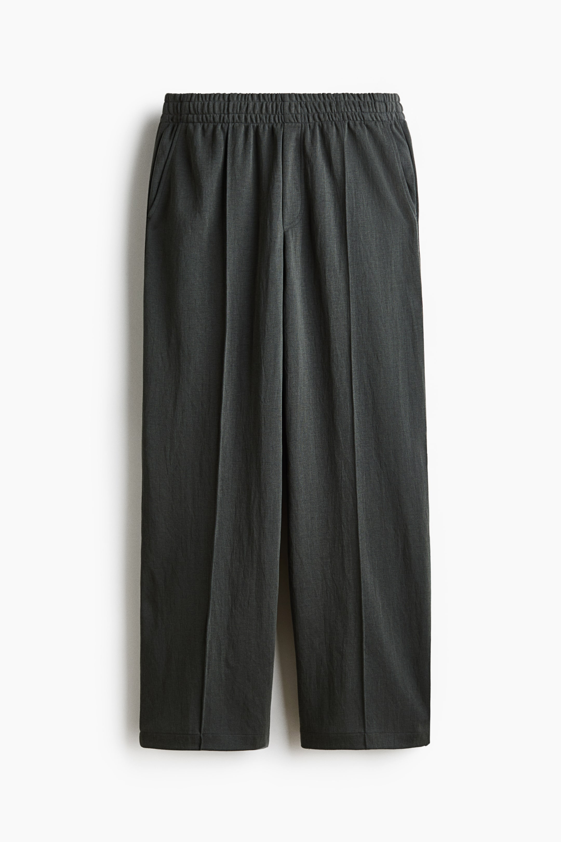 View larger image: The dark grey joggers are facing front, showcasing an elasticated waistband and side pockets. They feature a stitched faux fly and creases running down the front of the relaxed-fit legs.