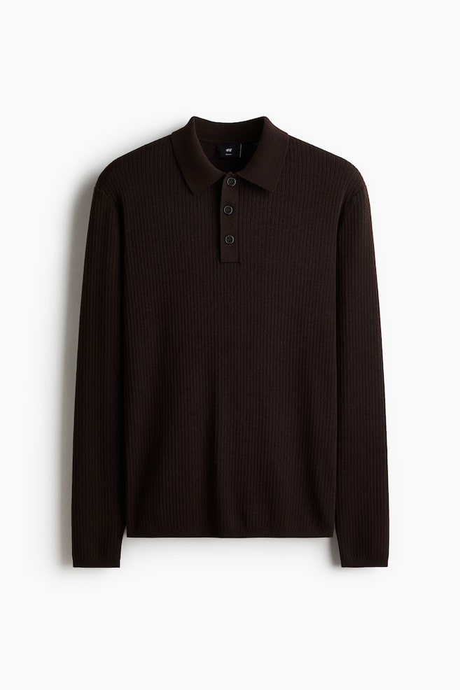 Una polo a maniche lunghe di colore marrone scuro viene presentata dal davanti, mostrando una texture a maglia a coste su tutta la superficie. Presenta un colletto classico, un'abbottonatura a tre bottoni con bottoni coordinati e polsini e orlo a coste. - 1