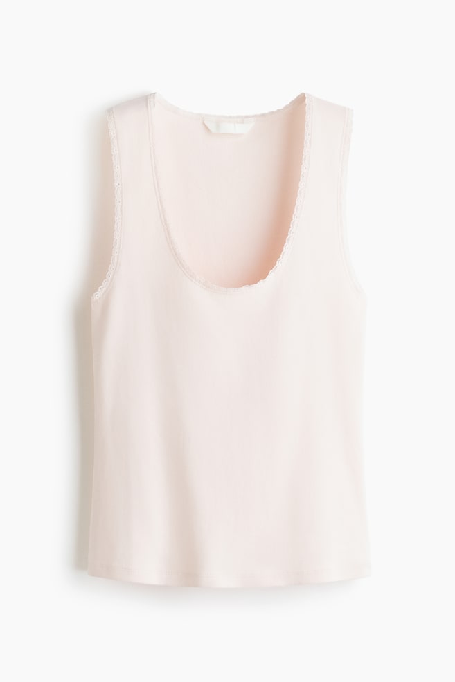 A light pink vest top featuring a scoop neckline and delicate white lace trimming around the neck and armholes. A plain white label is visible at the back of the neckline. - 1