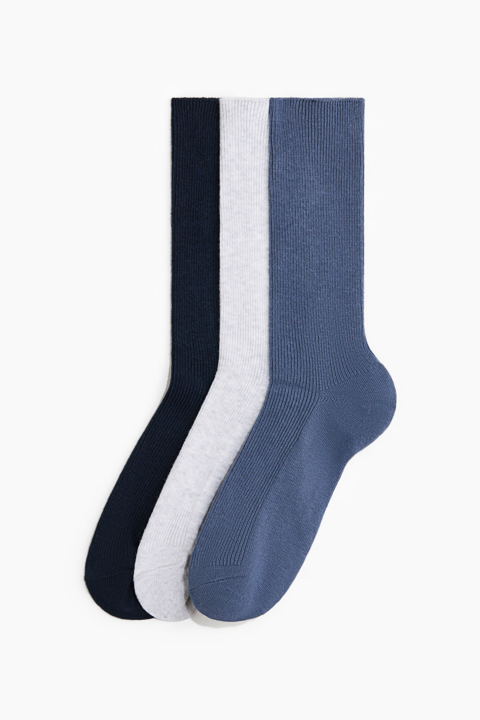 Tre paia di calzini a coste con scollo tondo in blu navy, grigio chiaro e blu medio, sovrapposti in una presentazione di profilo laterale. I calzini mostrano una fine texture verticale a coste che si estende dai polsini superiori fino al piede.