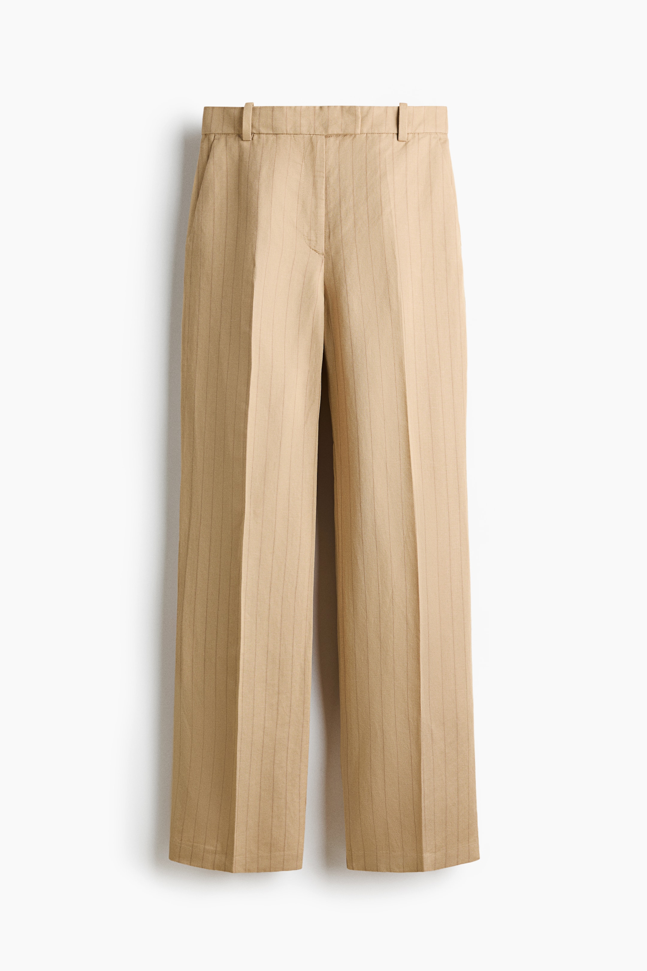 View larger image: Beige pinstriped trousers showcase a flat waistband with belt loops, side pockets, and distinct vertical creases running down the front of each wide leg.