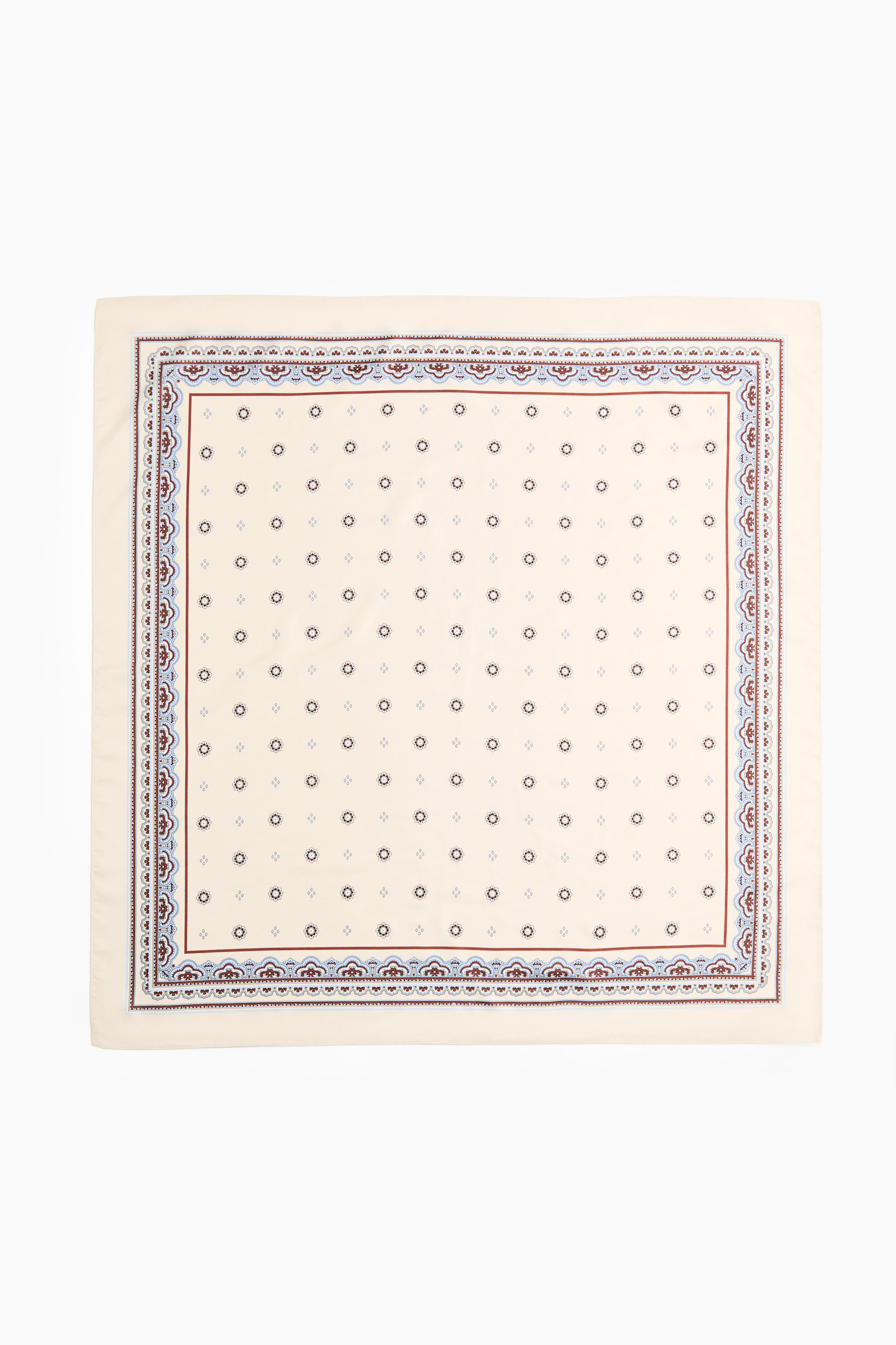 Ampliar la imagen: Una bufanda de tejido suave se coloca plana, con la parte FRONTAL hacia arriba, con un patrón impreso sobre un fondo crema claro. Está mostrando motivos geométricos pequeños en color gris oscuro y azul claro que se repiten, enmarcados por un borde intrincado que consiste en líneas rojas oscuras y formas festoneadas en azul claro y rojo oscuro.