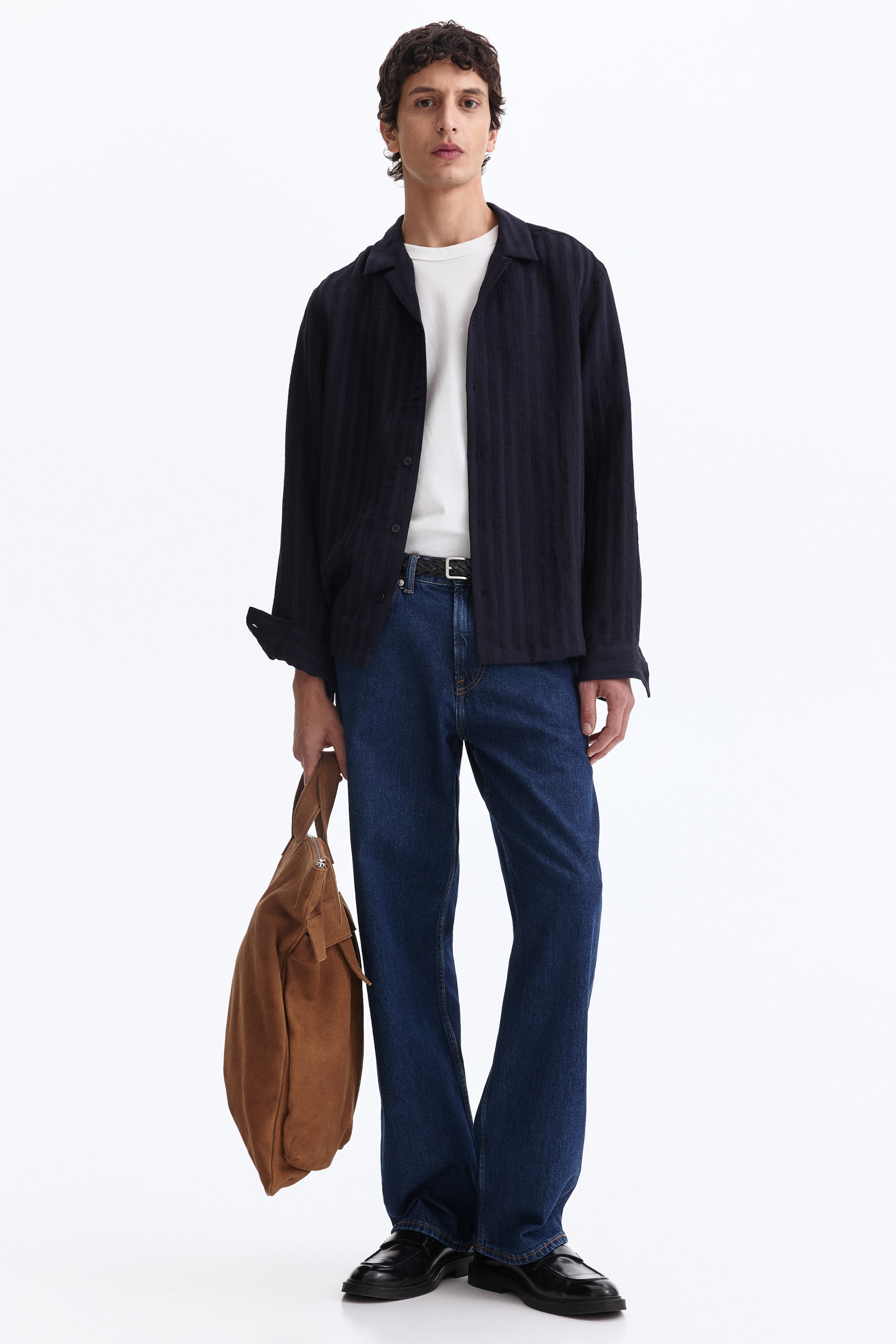 View larger image: A dark blue shirt with a textured weave, a resort collar, and a straight hem is worn by the model. Its long sleeves are rolled up, and the shirt is worn open over a white T-shirt, showcasing its regular fit.