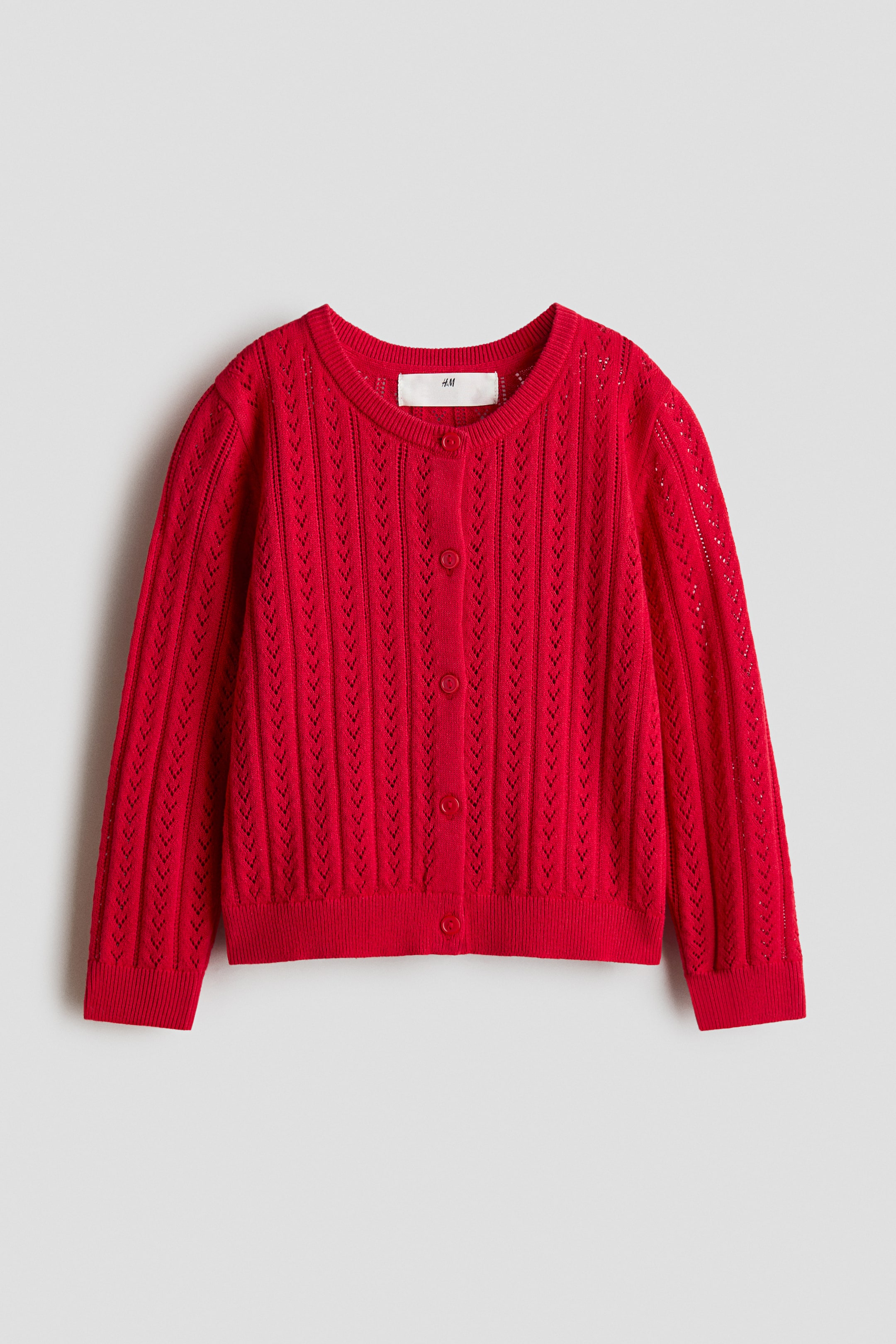 View larger image: A red cardigan is showcased from the front, highlighting its pointelle-knit cotton fabric. It features a round, rib-trimmed neckline, buttons running down the front, and ribbing finishing the cuffs and hem.