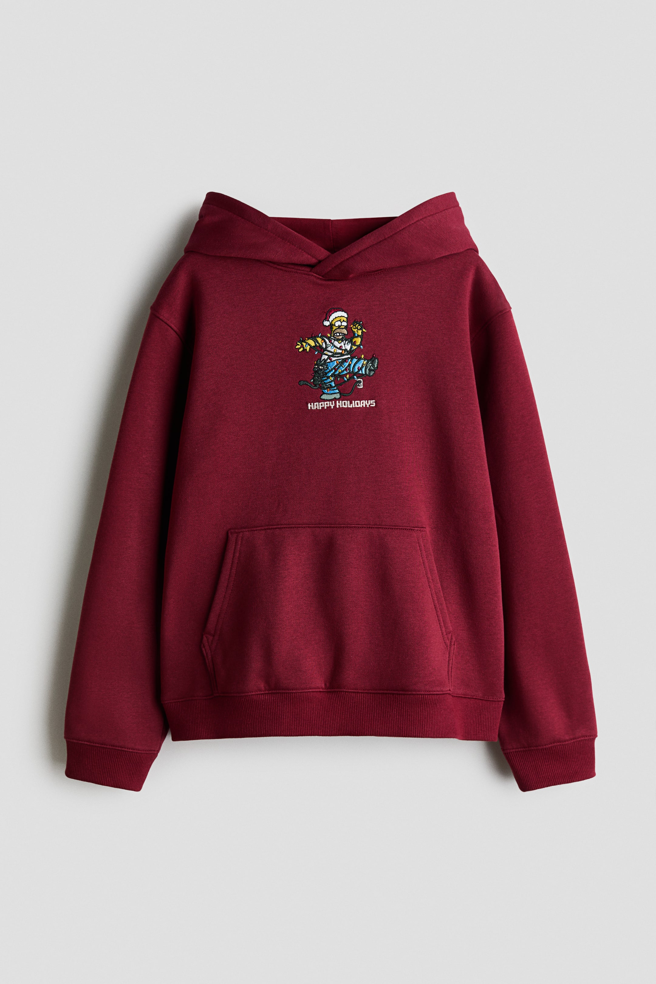 View larger image: A front view of a maroon fleece hoodie features a wrap hood, dropped shoulders, and a kangaroo pocket. The chest displays a printed graphic of a cartoon character tangled in holiday lights above the text "HAPPY HOLIDAYS", with ribbed detailing on the cuffs and hem.