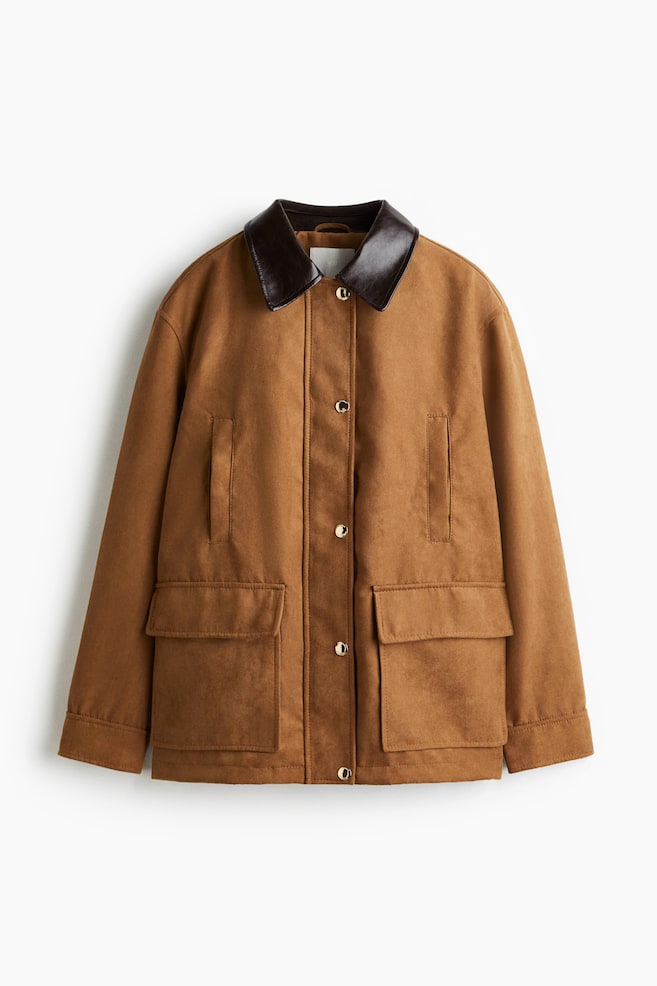 A brown utility jacket is facing front, featuring a contrasting dark brown pointed collar, gold-toned snap buttons along the front placket, two vertical welt chest pockets, and two large flap pockets near the hem. - 1