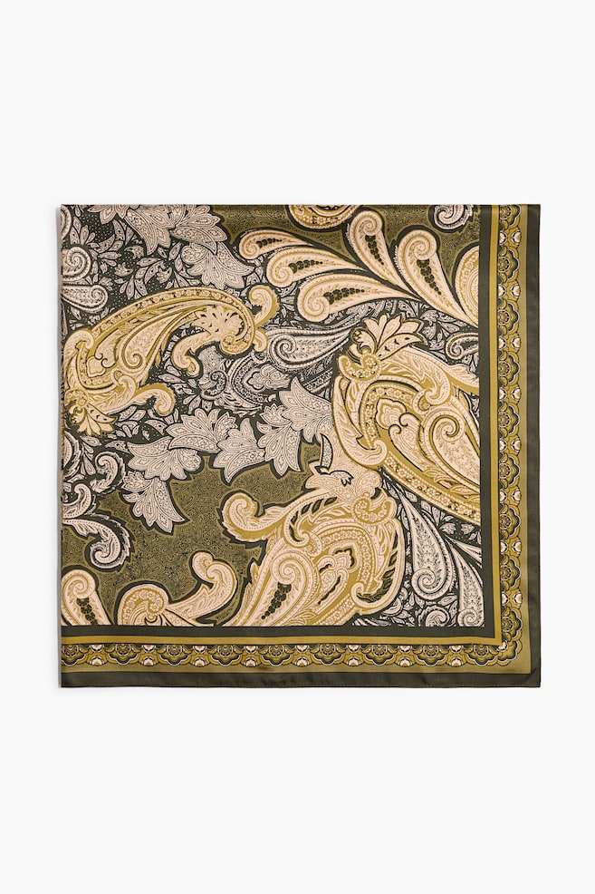A square scarf in a soft weave is laid flat, displaying an intricate paisley and floral pattern in shades of olive green, mustard yellow, beige and black. A decorative, multi-layered border frames the edges of the scarf. - 1
