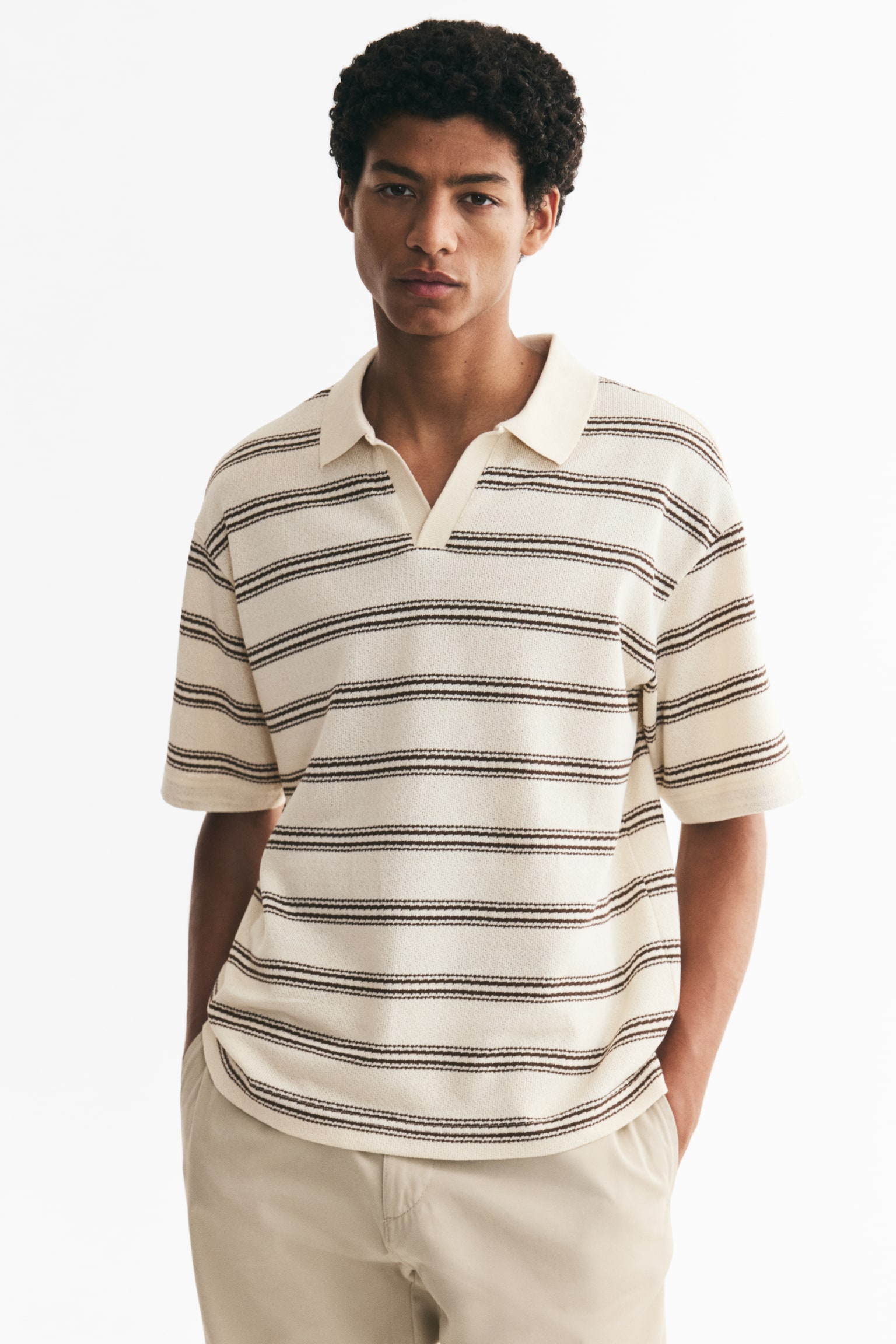 A cream knit polo shirt is shown from a front perspective, featuring multiple dark brown horizontal stripes made up of two thin lines. It is designed with a spread collar and a V-neck opening, and it displays short sleeves. - 1