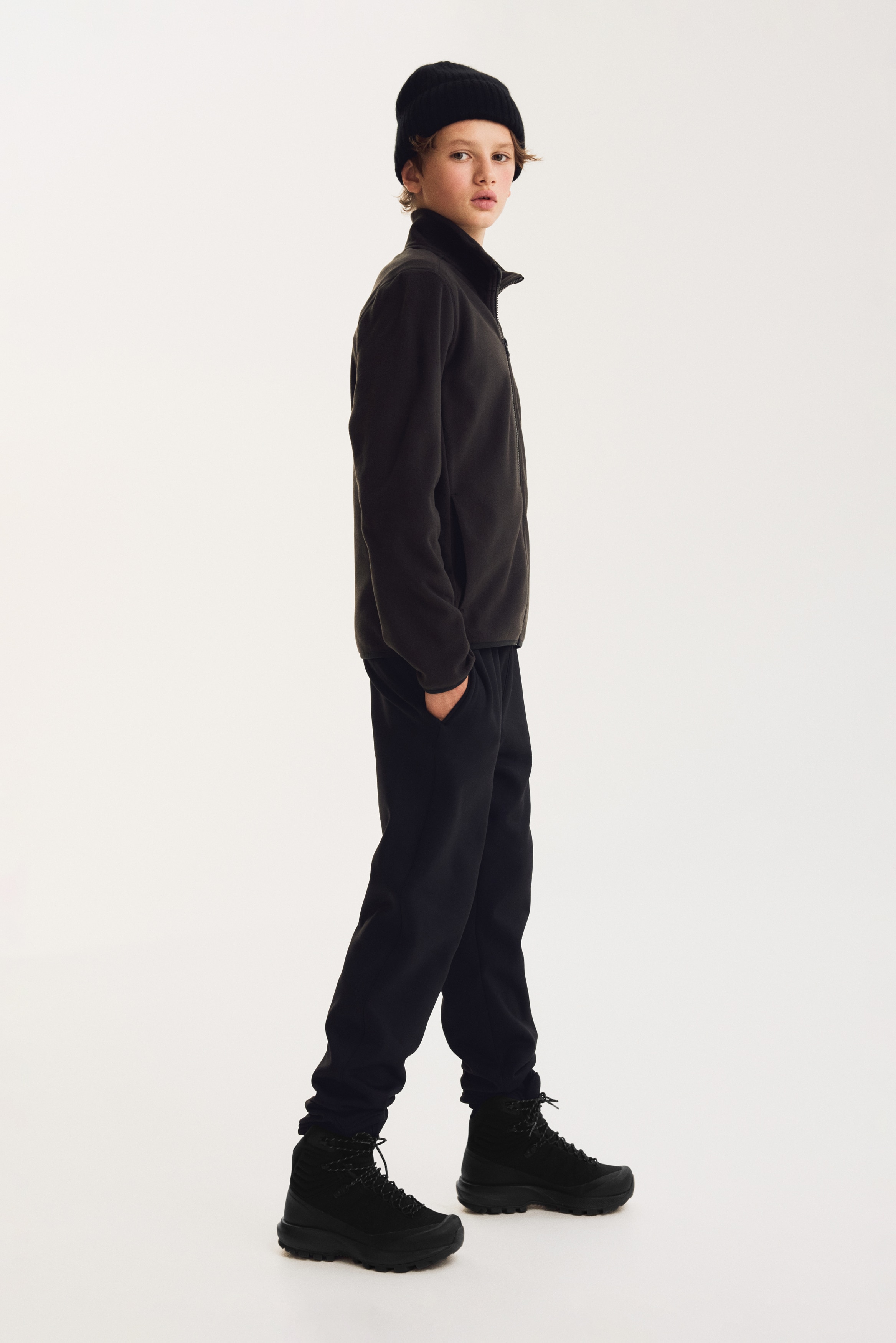 These black sweatpants are shown from the front, featuring a gathered elastic waistband with an adjustable drawstring. The trousers have a tapered leg silhouette with clean-finished hems.