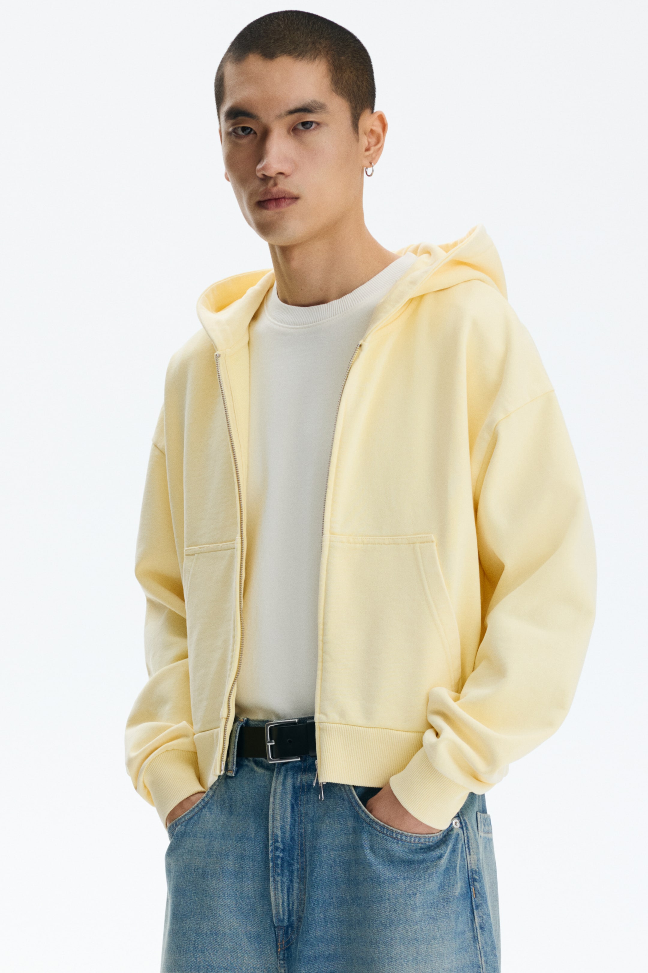 View larger image: A light yellow full-zip hooded sweatshirt is worn open over a white crewneck shirt, featuring a full-zip closure, split kangaroo pockets, and ribbed cuffs and hem.