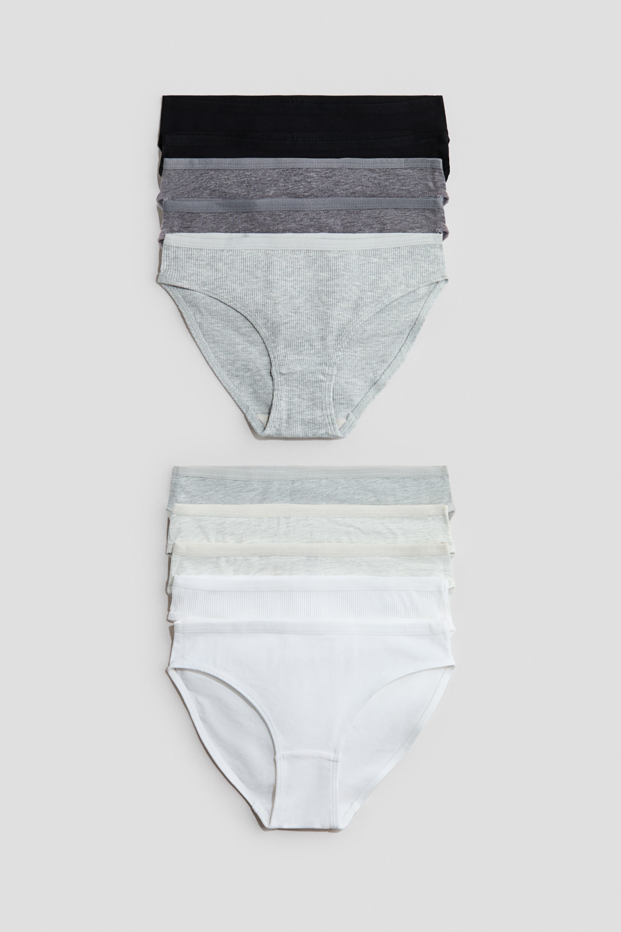 View larger image: Two stacks of women's briefs are showcased, each with a full brief at the front and multiple waistbands visible behind. The top stack highlights a light gray ribbed brief, with black and gray briefs stacked behind it, while the bottom stack displays a white smooth brief, with light gray and white briefs, some ribbed, stacked behind it.