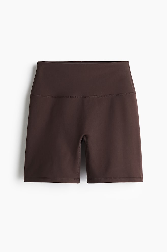 Los pantalones cortos de ciclismo deportivos se presentan como FRONT, en un color marrón oscuro. Presentan una cintura alta con una banda ancha y una costura horizontal debajo de la cintura, extendiéndose hasta la mitad del muslo. Los pantalones cortos están confeccionados con una tela suave, mostrando costuras visibles a lo largo de las piernas exteriores y una costura contorneada en la entrepierna. - 1