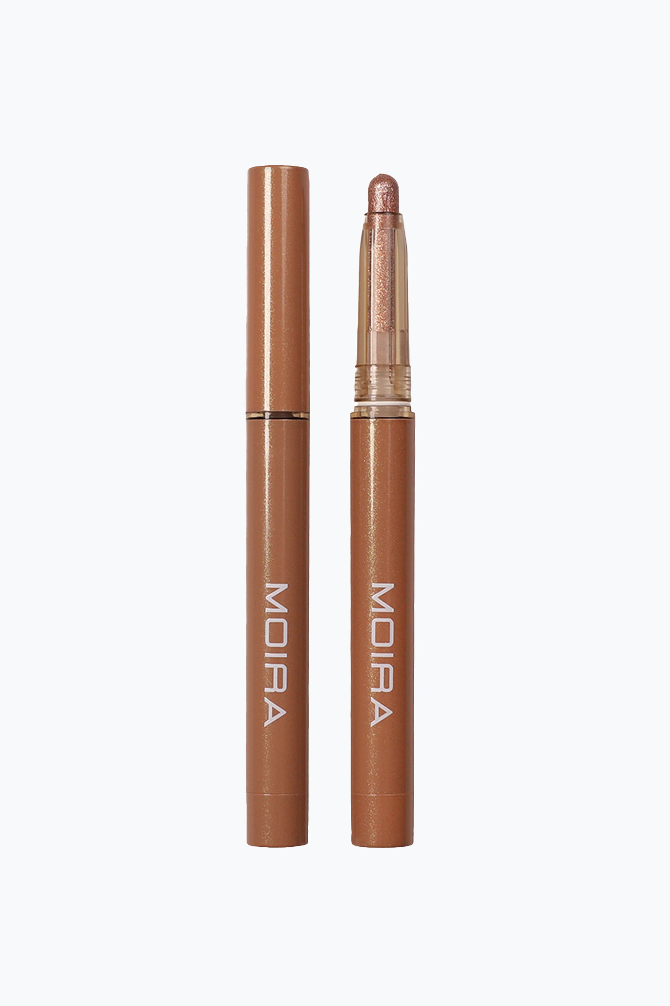 Vis større bilde: Stellar Glaze Stick Shadow vises som to slanke, sylindriske sminkepenner som står oppreist side om side. Pennen til venstre har en lukket, metallisk bronsefarget hette, mens pennen til høyre er avdekket og viser en skimrende bronsefarget øyenskyggetupp i en gjennomsiktig plastkrage. Begge pennene har merkenavnet «MOIRA» trykt vertikalt i hvite versaler på de matchende bronsefargede hylsene.