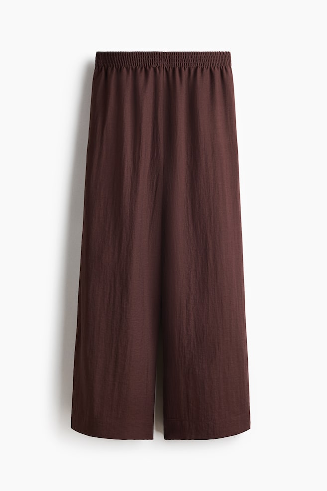 Dark brown wide-leg cropped trousers are presented from the front, featuring an elasticated waistband and a slightly textured fabric. - 1