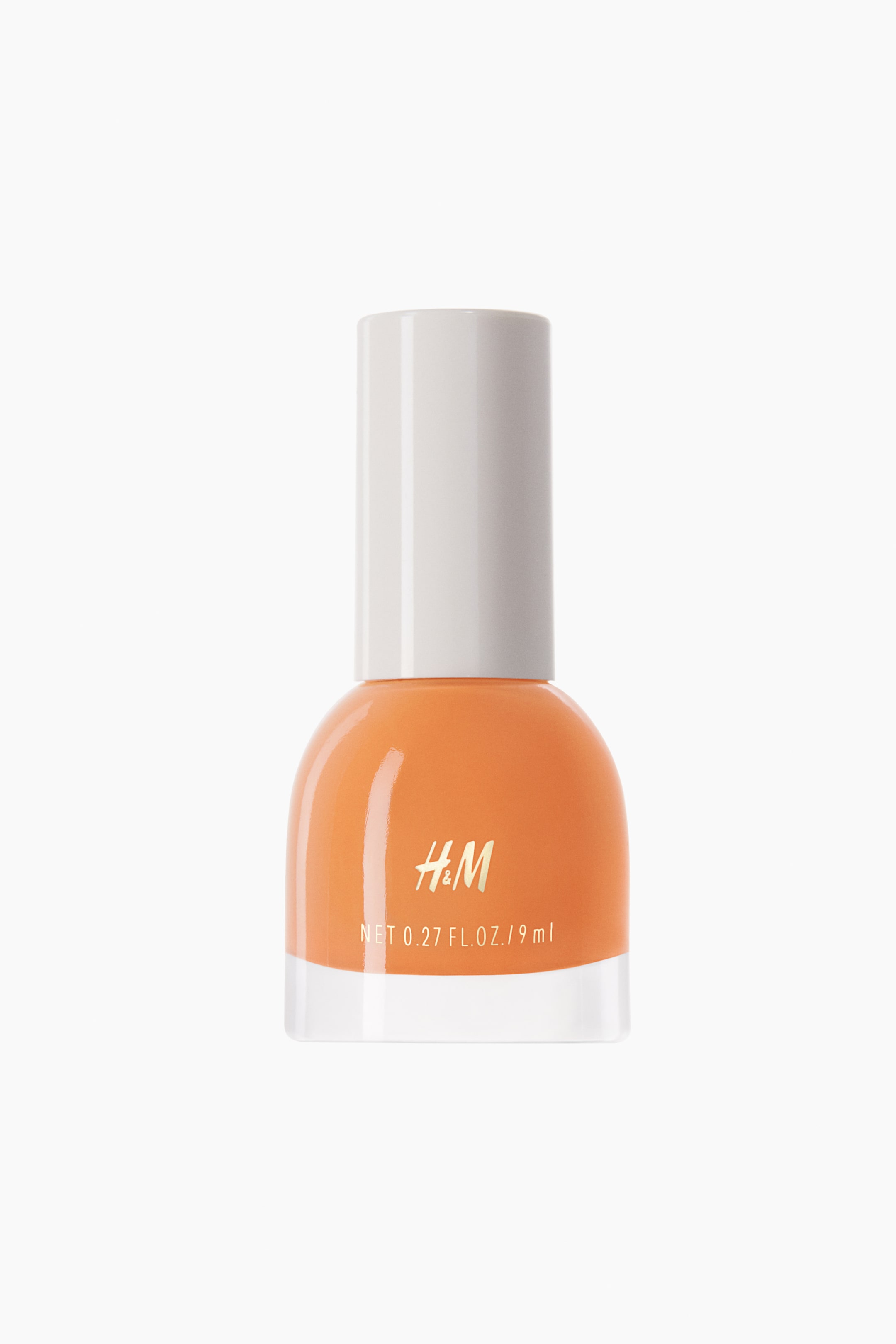 View larger image: An orange nail polish bottle is standing upright, featuring a clear, rounded glass base filled with orange polish and a white, cylindrical cap. The "H&M" logo is appearing in gold on the bottle, with the net weight "0.27 FL. OZ. / 9 ml" printed in black below it.