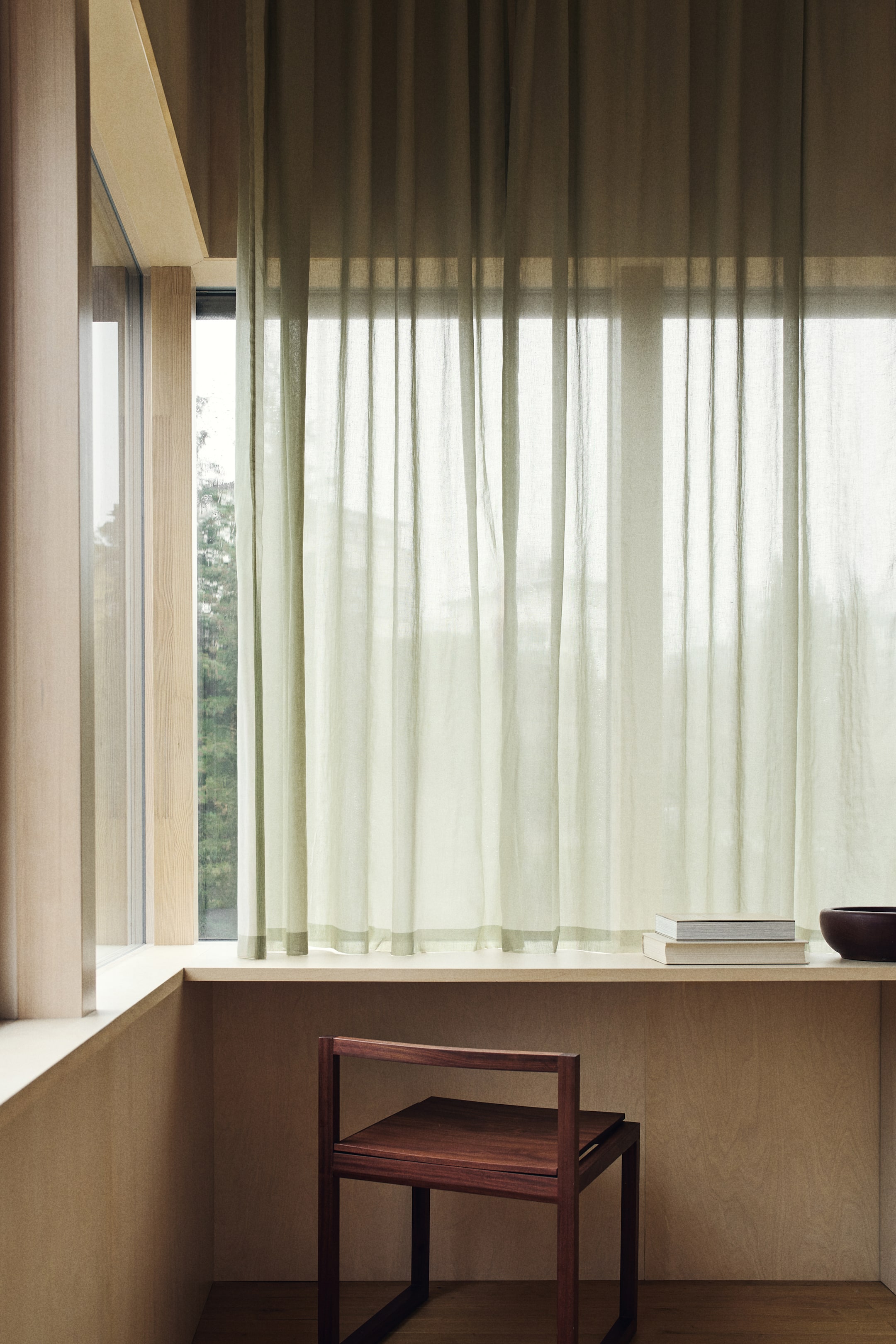 Ampliar la imagen: Cortinas de gasa verde salvia cuelgan en pliegues verticales suaves, vistas desde el frente, con un panel sólido más oscuro visible arriba. Presentan un dobladillo verde más oscuro en el borde inferior.