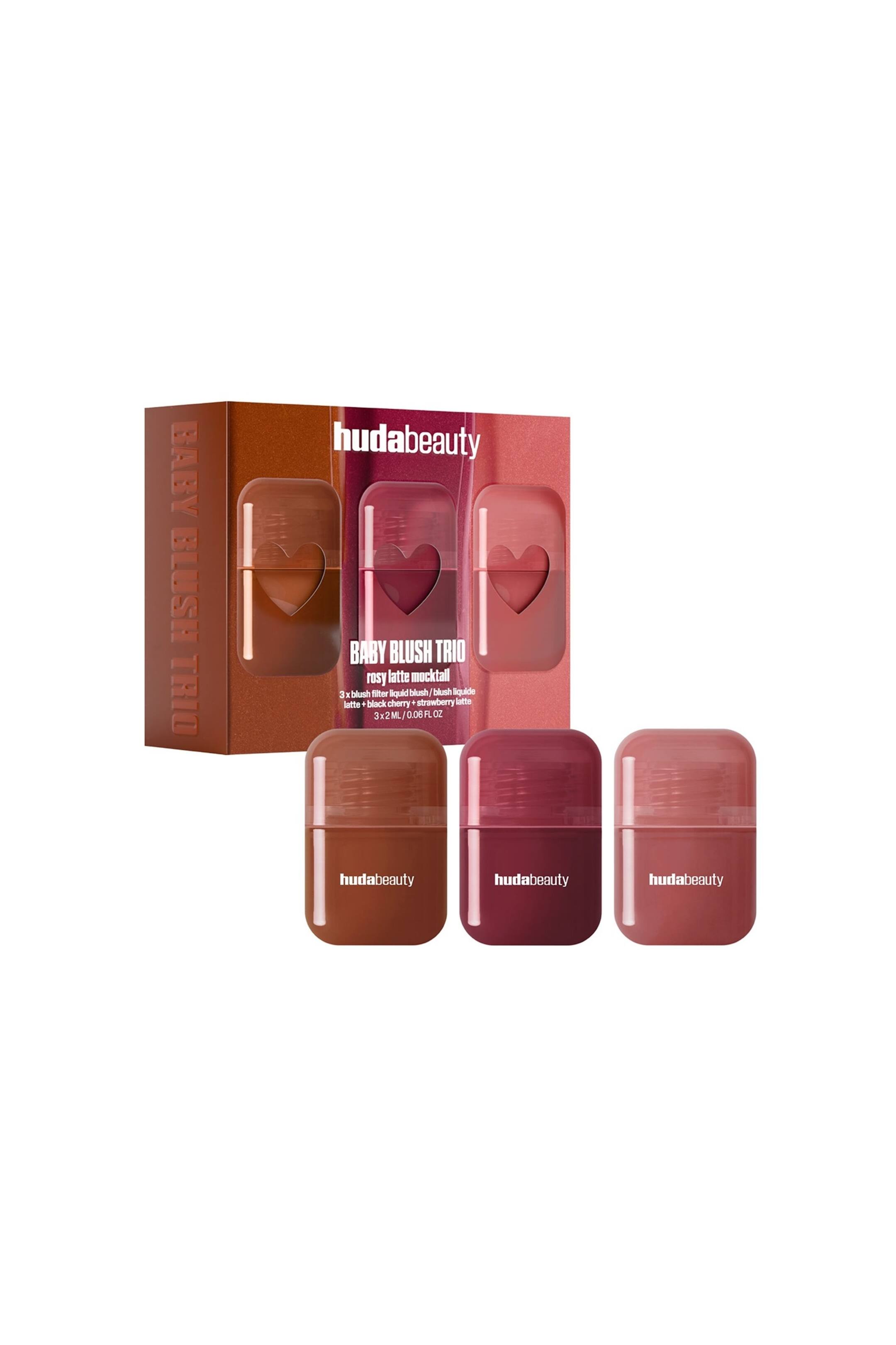 Näytä suurempi kuva: Baby Blush Mocktail Trio esittelee kolmen nestemäisen poskipunan setin, jossa on suorakulmainen pakkauslaatikko hieman sivulle käännettynä sekä kolme pientä, pyöristetyn suorakulmaista pulloa etualalla. Pulloissa näkyy kolme eri sävyä?lämmintä ruskeaa, syvää marjapunaista ja pölyistä roosaa?ja jokaisessa on brändinimi "hudabeauty" valkoisella tekstillä, kun taas laatikossa on vastaavat väriblokatut paneelit sydämenmuotoisilla ikkuna-aukoilla.