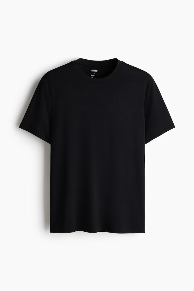 A black T-shirt is shown from the front, featuring a crew neck and short sleeves. A white brand label is visible on the inner back of the collar. - 1
