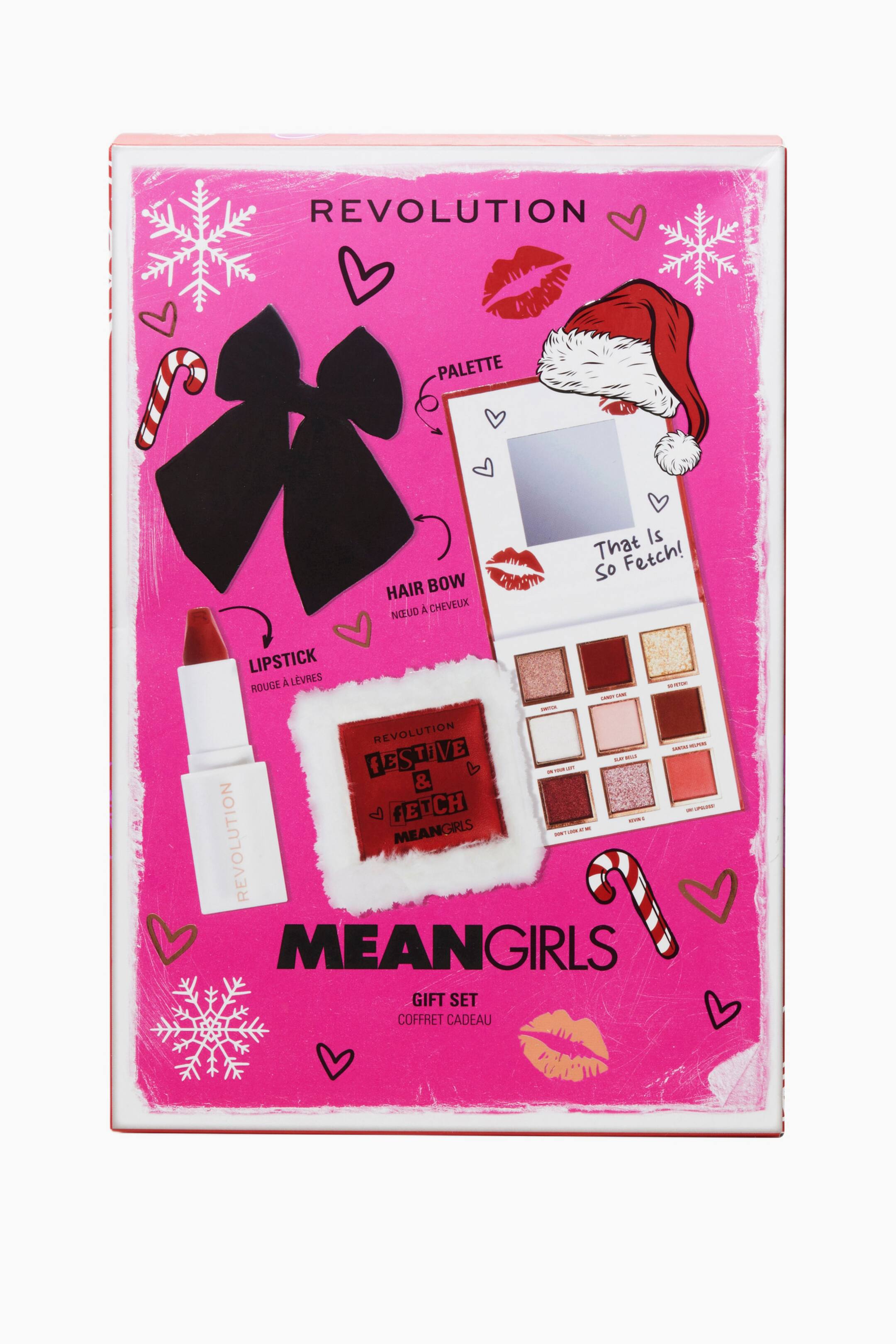 Größeres Bild ansehen: Ein Mean Girls x Revolution Weihnachtsgeschenkset präsentiert seinen Inhalt auf einer leuchtend pinkfarbenen, rechteckigen Box mit festlichen Grafiken. Auf der Vorderseite sind eine große schwarze Haarschleife, ein weißer Lippenstiftstift mit rotem Lippenstift, ein rotes Satin-Beutelchen mit weißem Kunstpelzbesatz und eine geöffnete Lidschattenpalette mit neun Farbtönen zu sehen.