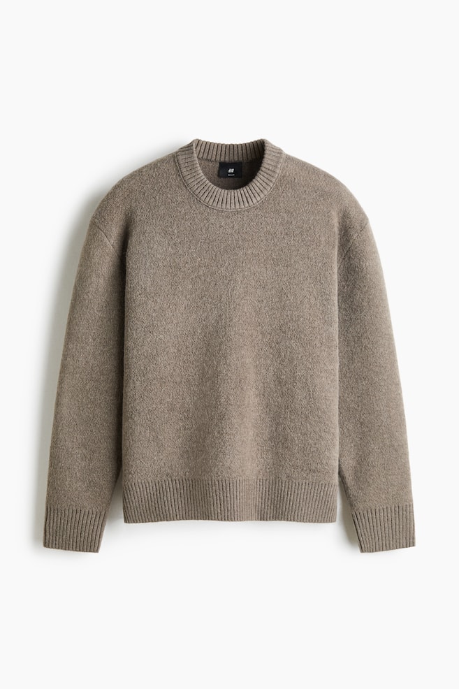 En taupebrun striktrÃ¸je er vist forfra og fremhÃ¦ver et blÃ¸dt, struktureret stof med en klassisk rund halsudskÃ¦ring. Designet har en kraftig ribbet krave, sÃ¦nkede skuldre, lange Ã¦rmer med ribbede manchetter og en matchende ribkant forneden. - 1