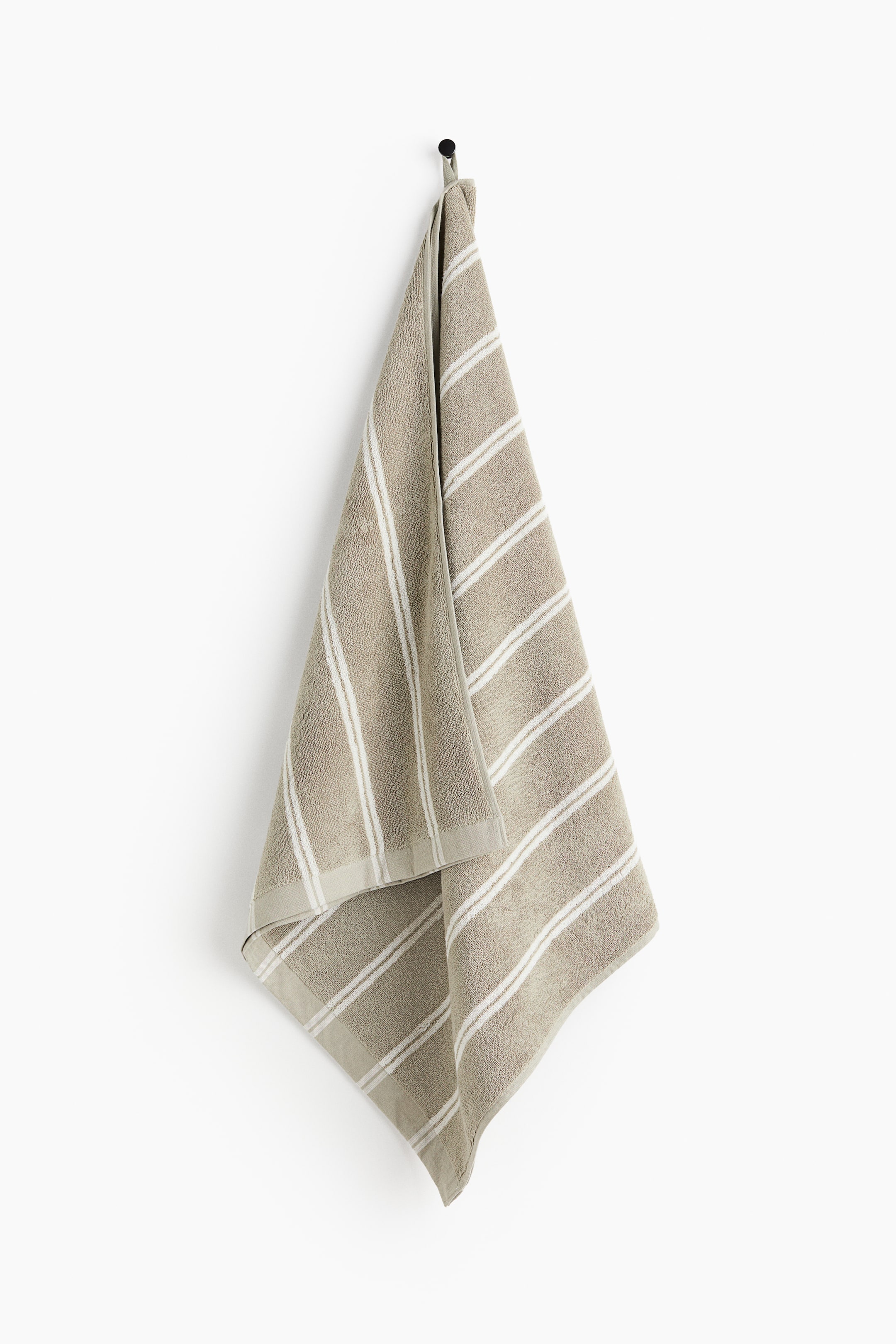 View larger image: A taupe terry towel is showcasing its front, adorned with horizontal white stripes of varying widths. The towel is neatly folded over at the top, creating a draped, triangular formation.