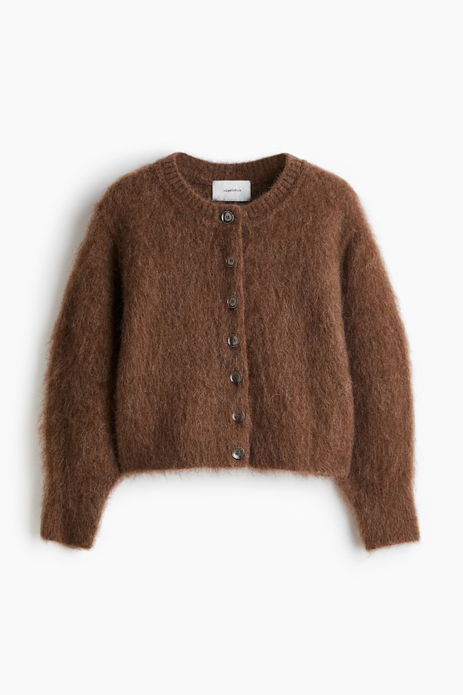 A short brown cardigan is presented from the front, featuring a fuzzy knit texture. It is designed with a round neckline, buttons down the front, 3/4-length sleeves, and ribbing at the neckline, cuffs, and hem. - 1