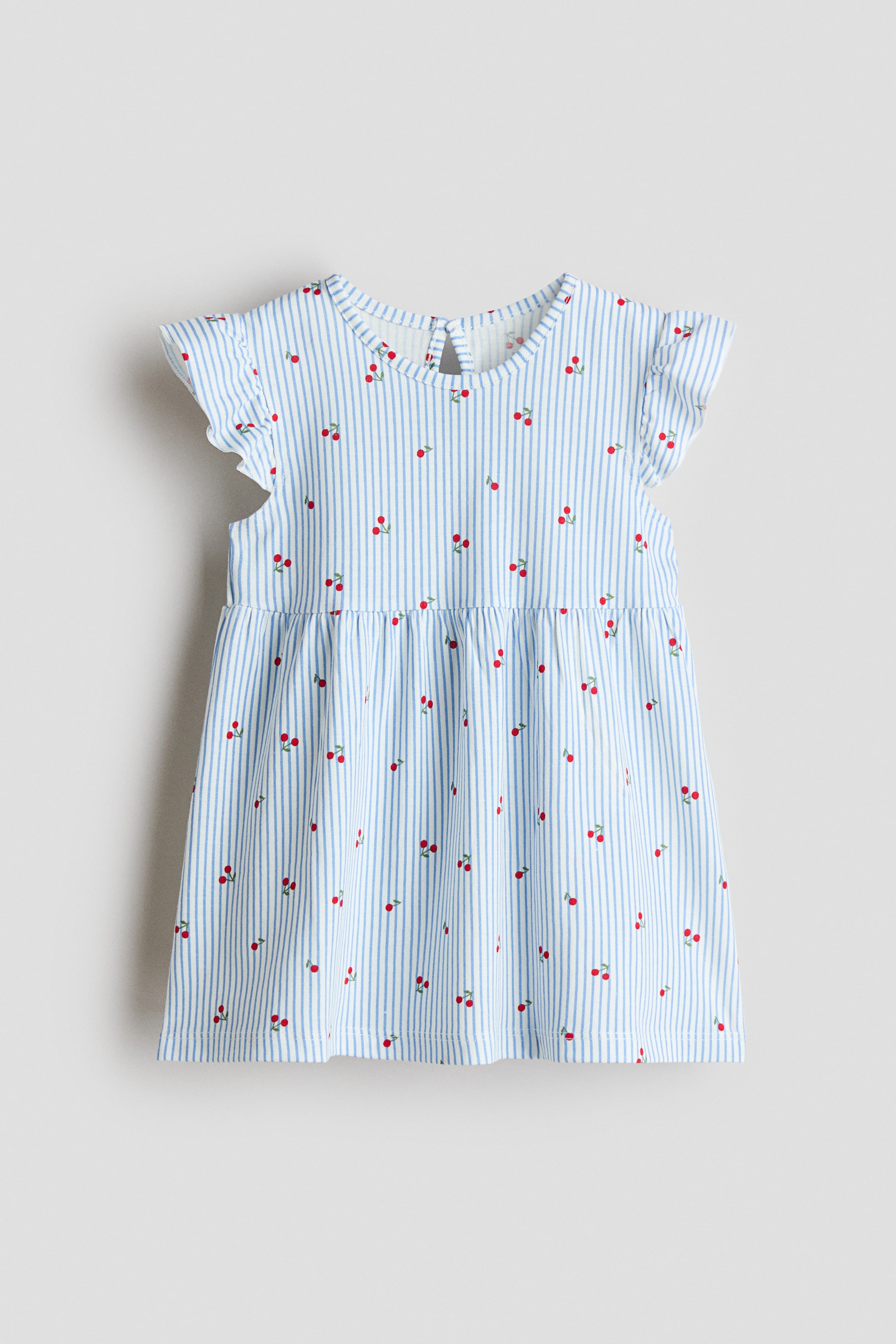 Grotere afbeelding bekijken: De babyjurk heeft een witte achtergrond met dunne blauwe verticale strepen en verspreide rode kersenprints, gepresenteerd als VOORKANT. Hij is ontworpen met een ronde halslijn, gerimpelde kapmouwtjes en een geplooide taille, met een sleutelgatopening en een zichtbare knoop aan de achterkant van de nek.