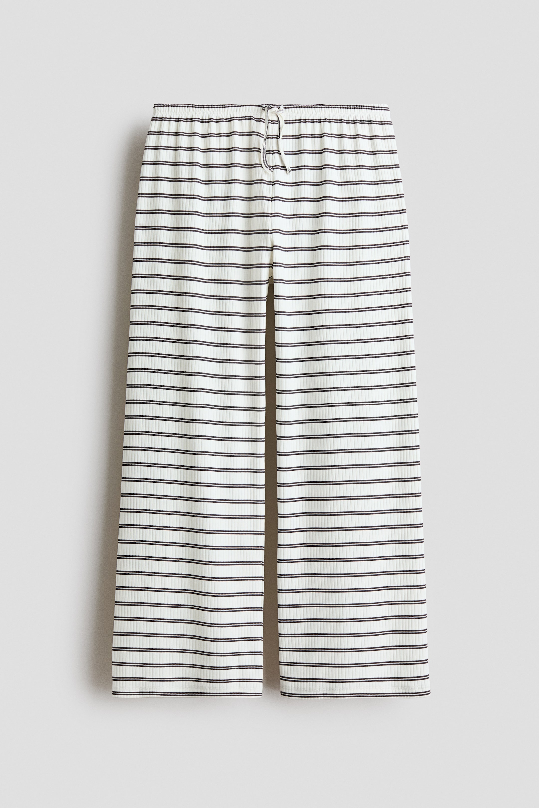 View larger image: Pyjama bottoms are crafted from a ribbed cotton jersey fabric, featuring an elasticated, drawstring waist and straight legs. They showcase a pattern of thin, horizontal off-white and dark grey stripes, presented from the front.
