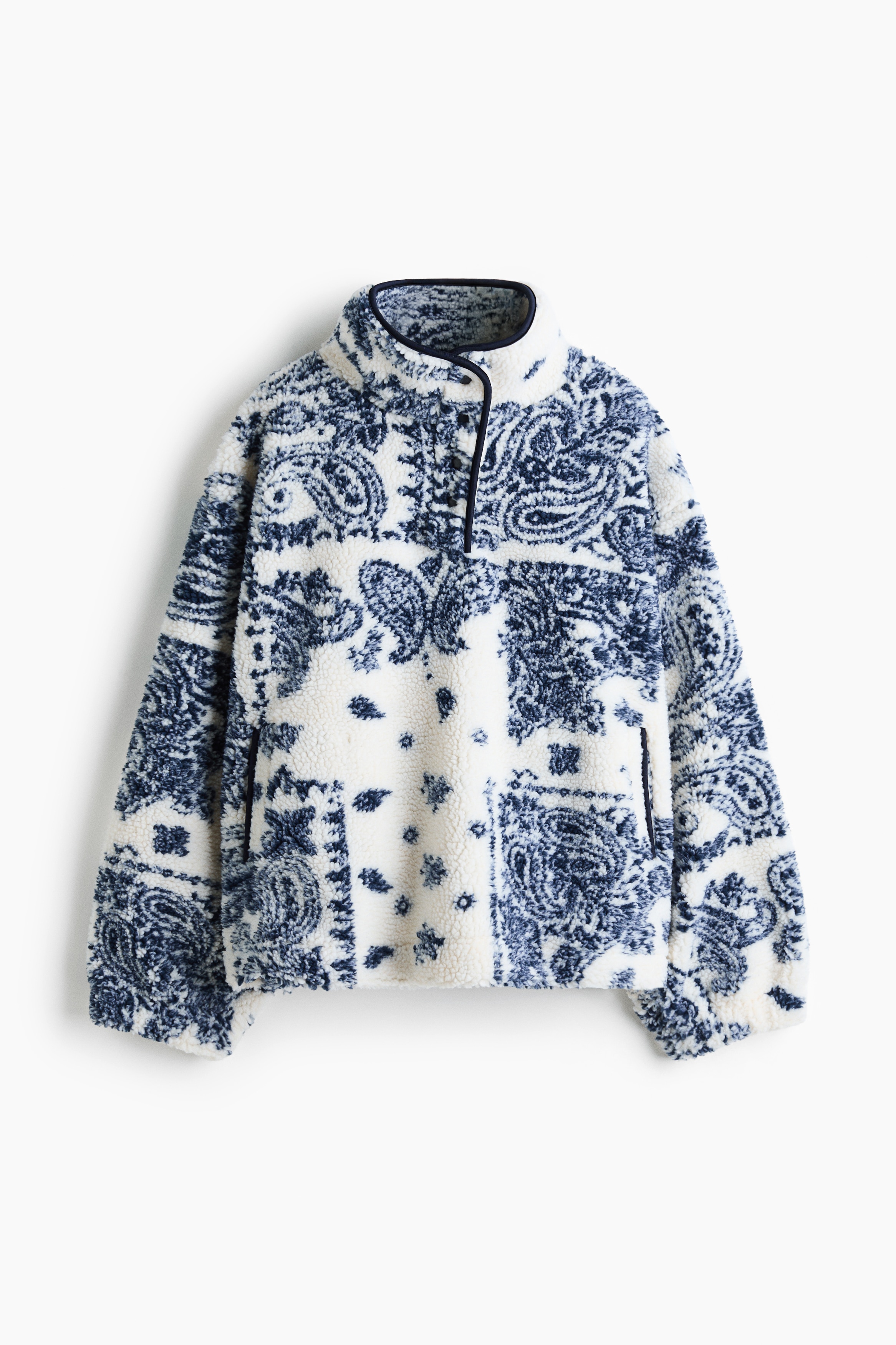 A soft teddy fleece sweater with a cream and dark blue printed design is being worn by the model. The sweater features a high stand collar with black narrow binding and a buttoned front placket.