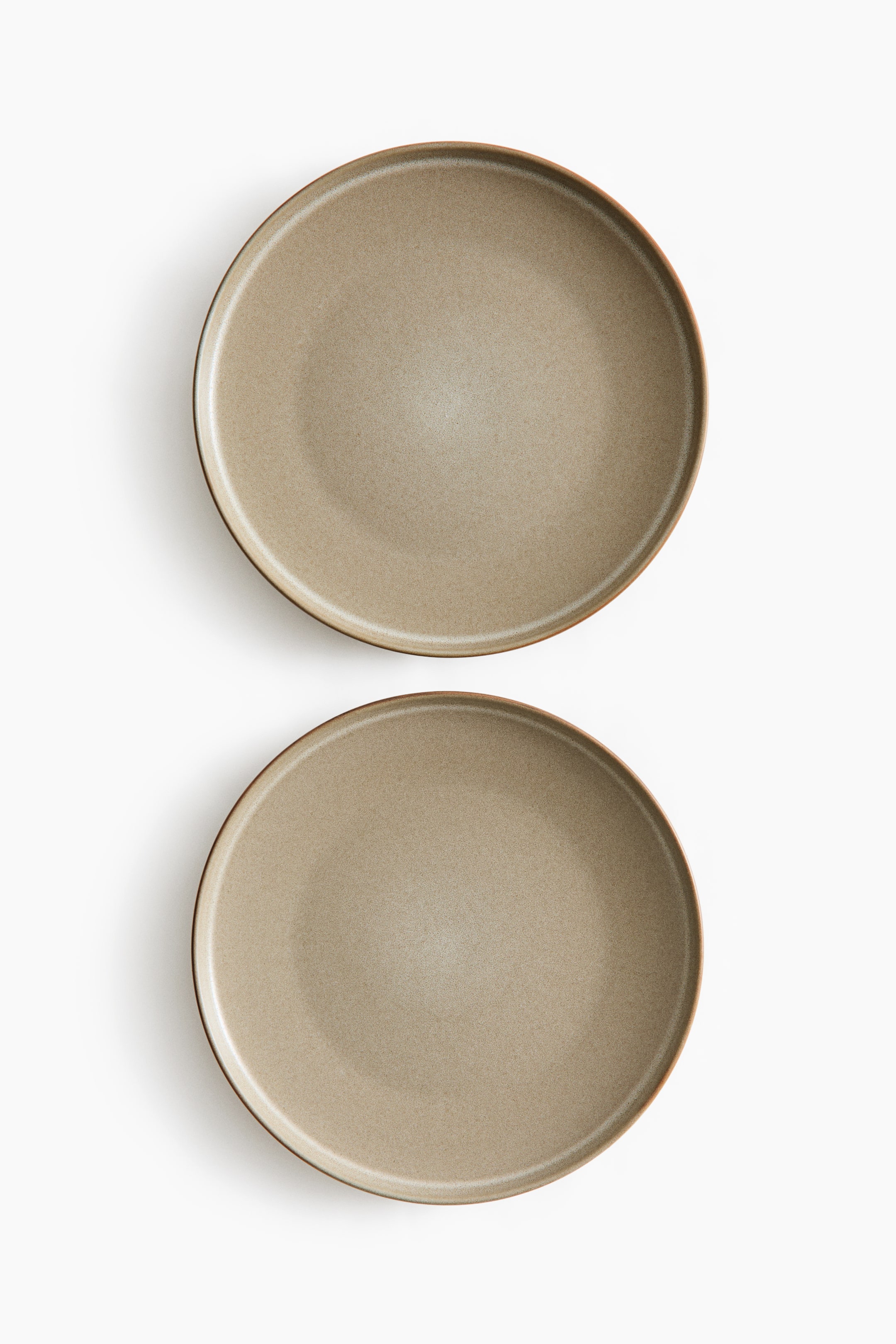 View larger image: Two round stoneware dinner plates feature a reactive glaze that creates variegated taupe and brown coloring, with each plate displaying a subtle darker rim and a unique appearance.