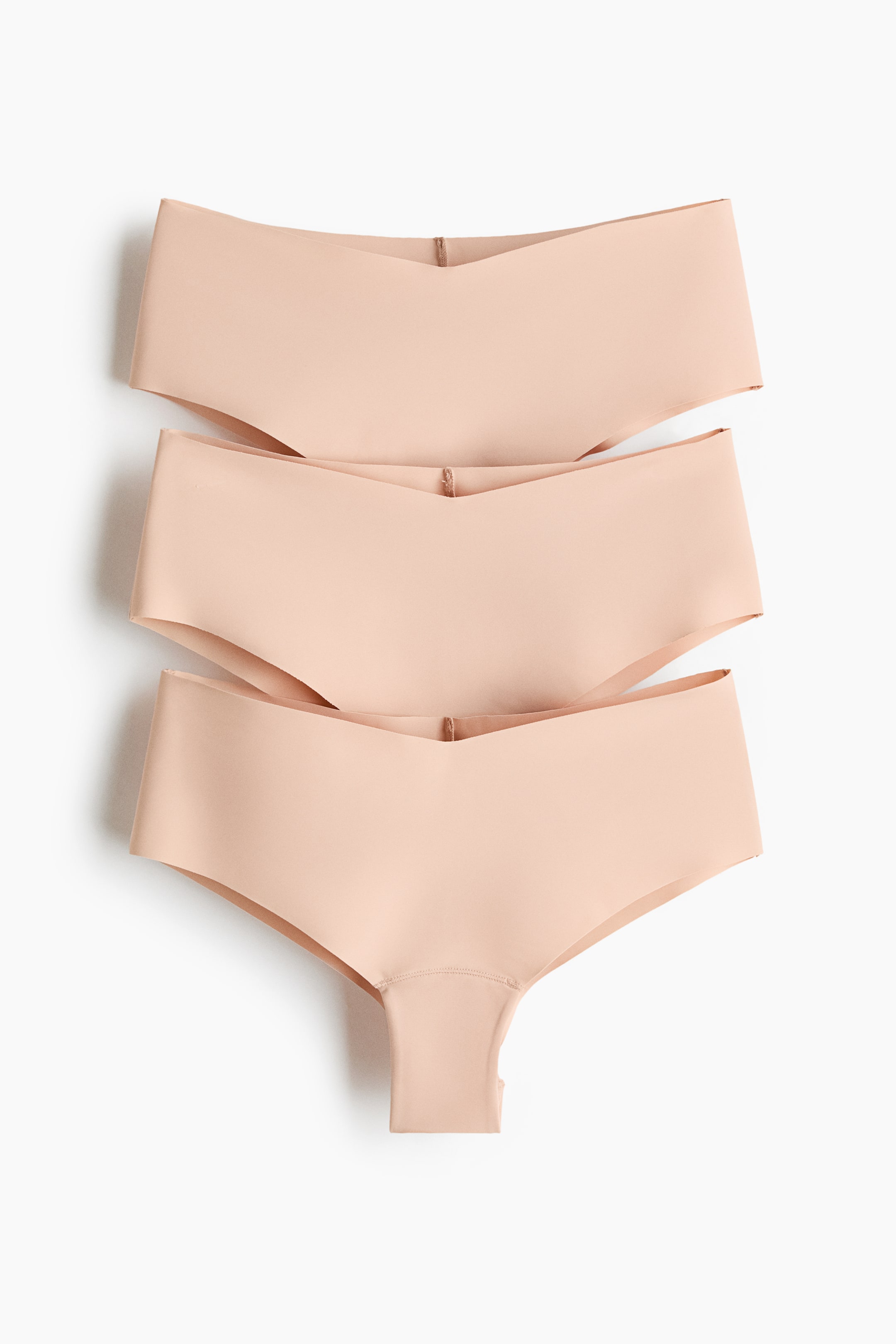 View larger image: Three pairs of nude seamless knickers are stacked vertically, each showcasing a front view with a V-shaped waistband and smooth, laser-cut edges.