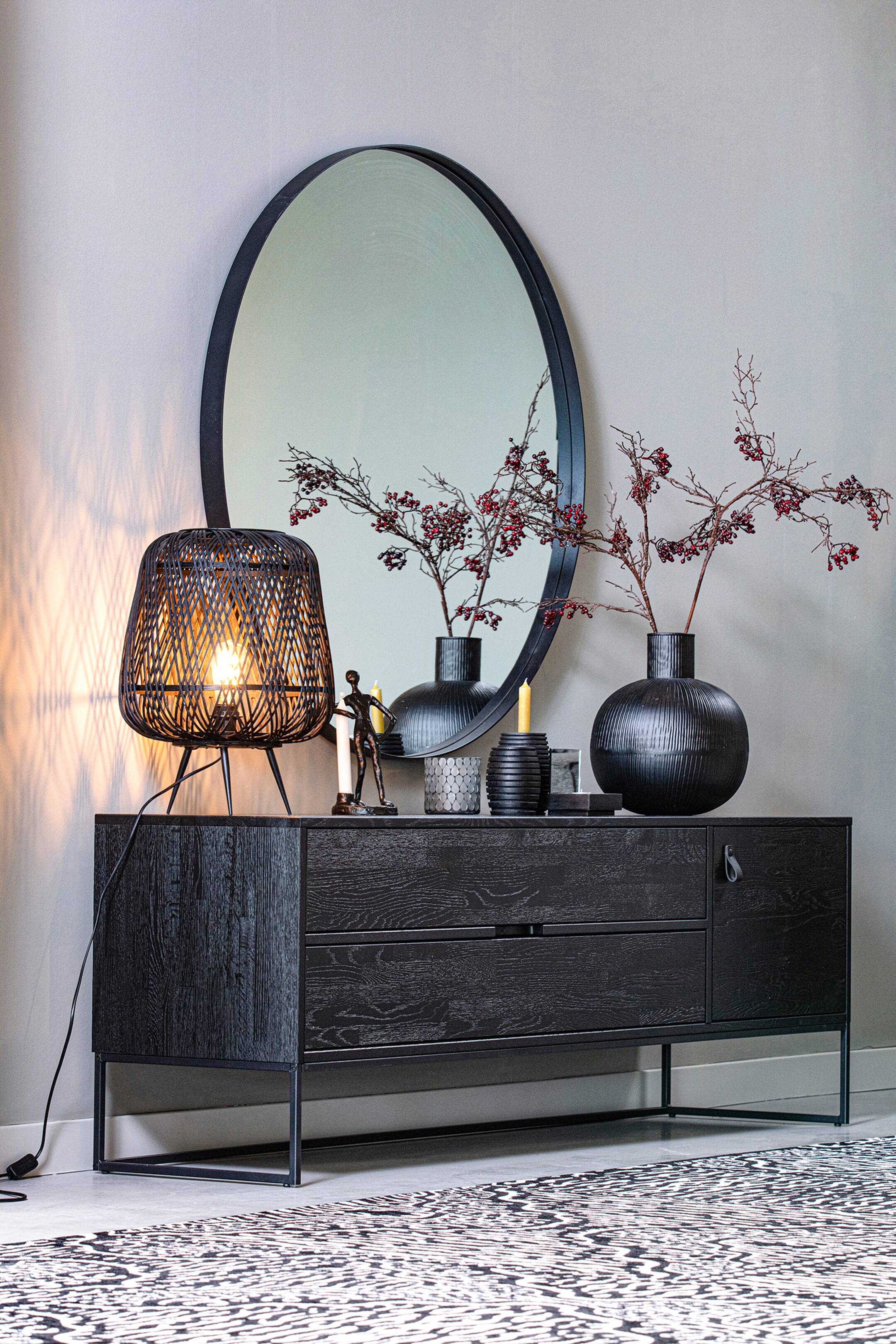 Größeres Bild ansehen: Ein schwarzes Holz-Sideboard mit einer strukturierten Holzmaserung zeigt seine Vorder- und linke Seite. Es verfügt über zwei Schubladen auf der linken Seite und eine Tür mit einem Ledergriff auf der rechten Seite, die alle auf einem dünnen schwarzen Metallrahmen ruhen.