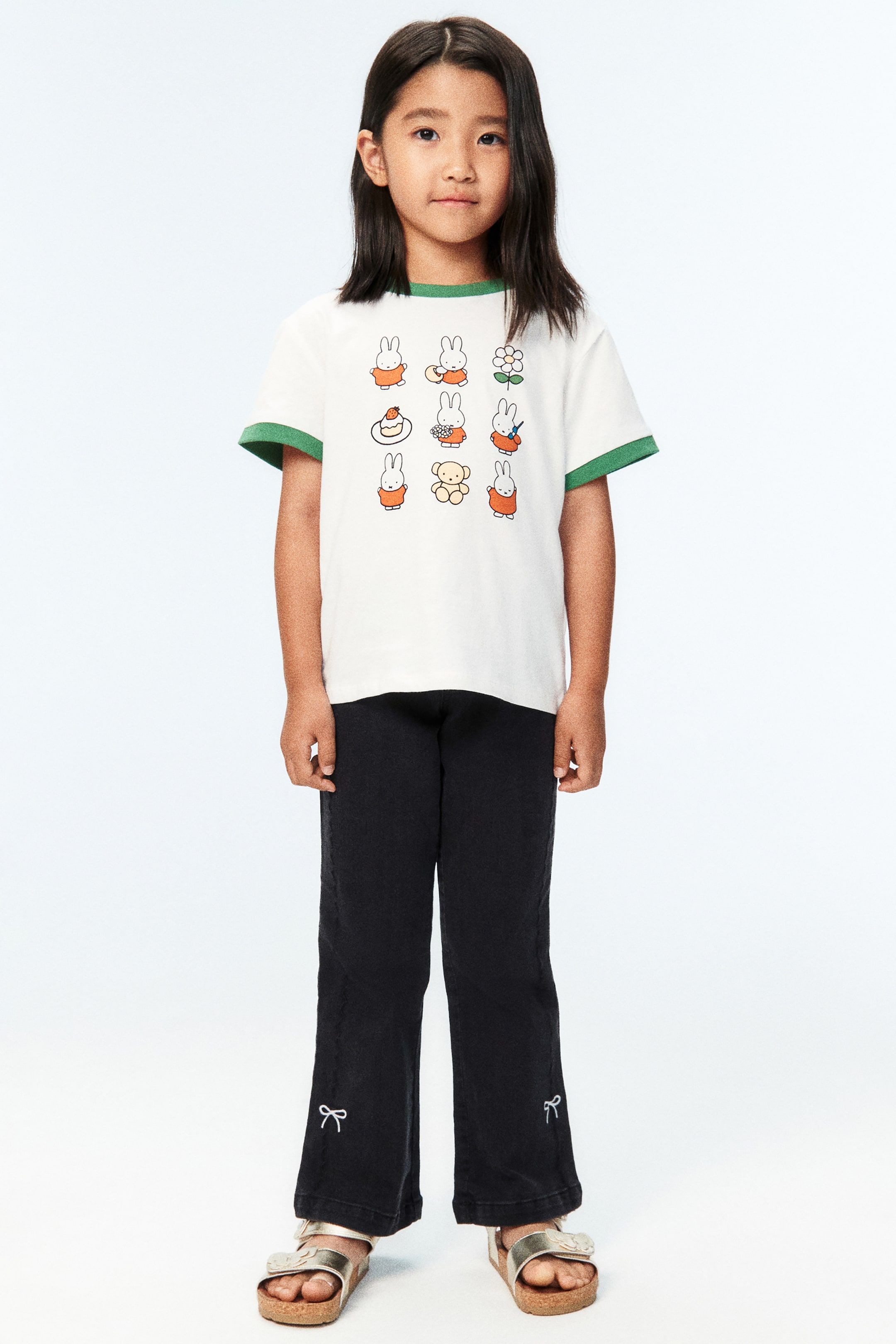 View larger image: The model is wearing dark-coloured jeans with a regular fit through the hips and thighs, flared legs, and white bow embroidery on the lower front.