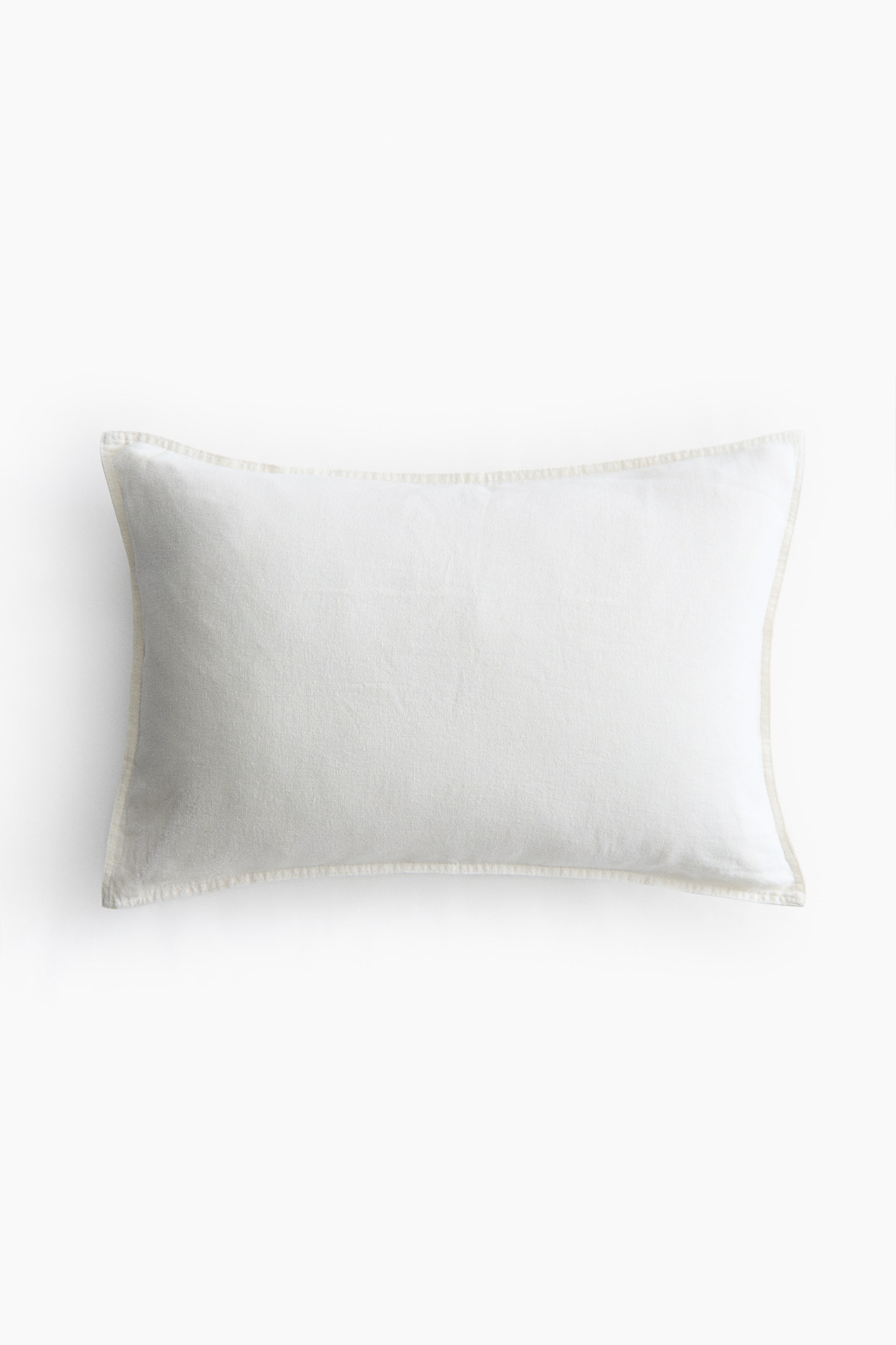 View larger image: The cushion cover showcases its front, crafted from an off-white linen and cotton blend. It highlights prominent stitching along its edges.