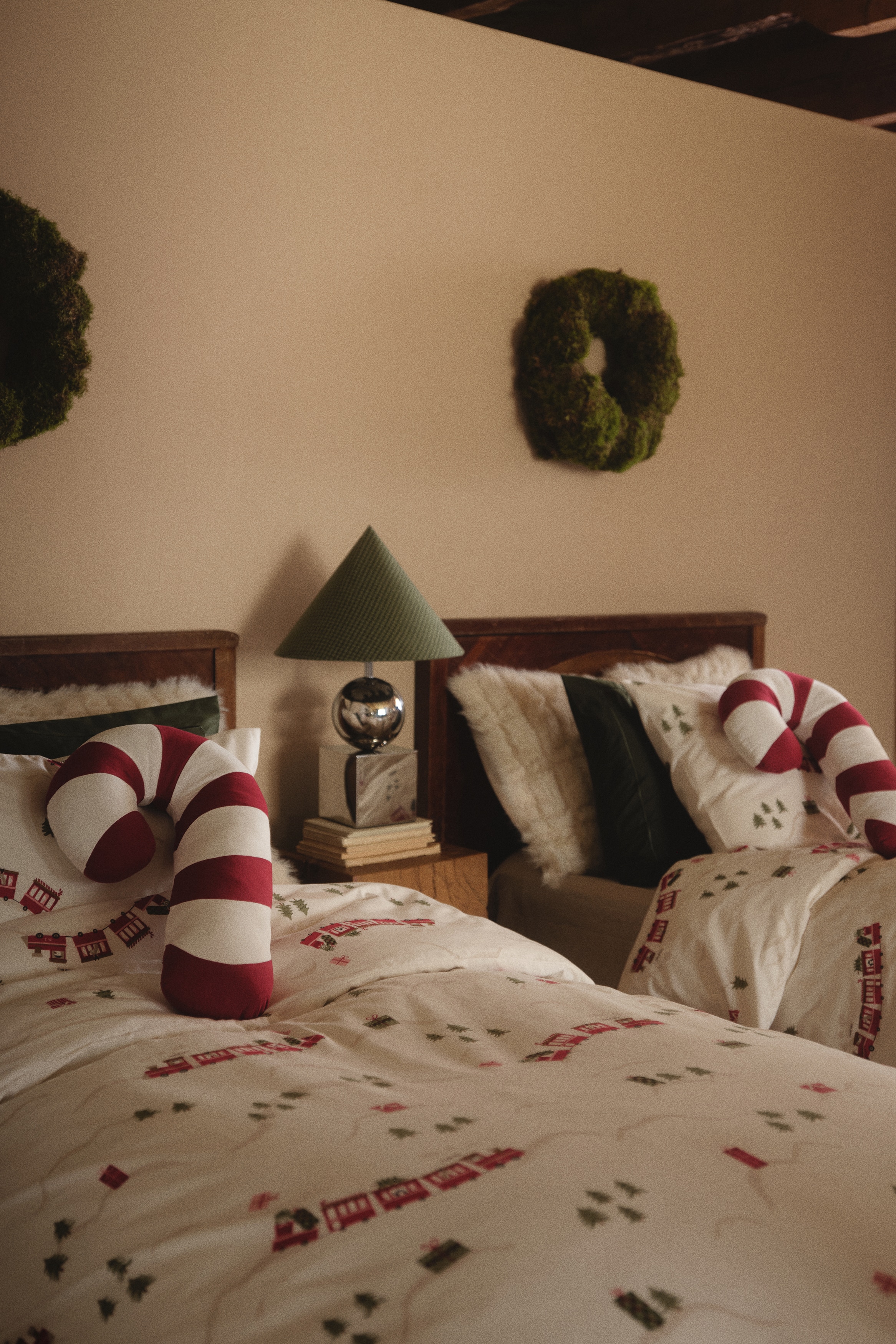 A plush candy cane-shaped cushion is facing front, featuring alternating diagonal stripes of red and white. The cushion has a soft, rounded, and stuffed construction with a smooth fabric cover.