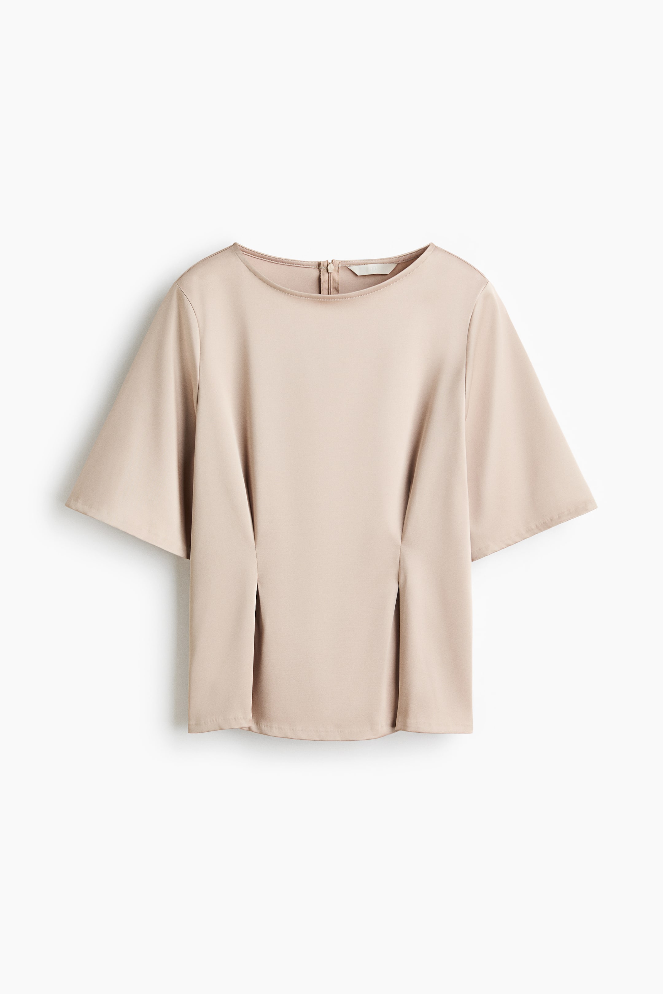 Ver imagem maior: Uma blusa em bege‑claro é apresentada de frente, com decote redondo e mangas curtas e largas. Na parte de trás da gola é visível um fecho de correr, e duas pregas verticais criam uma queda estruturada na parte da frente.
