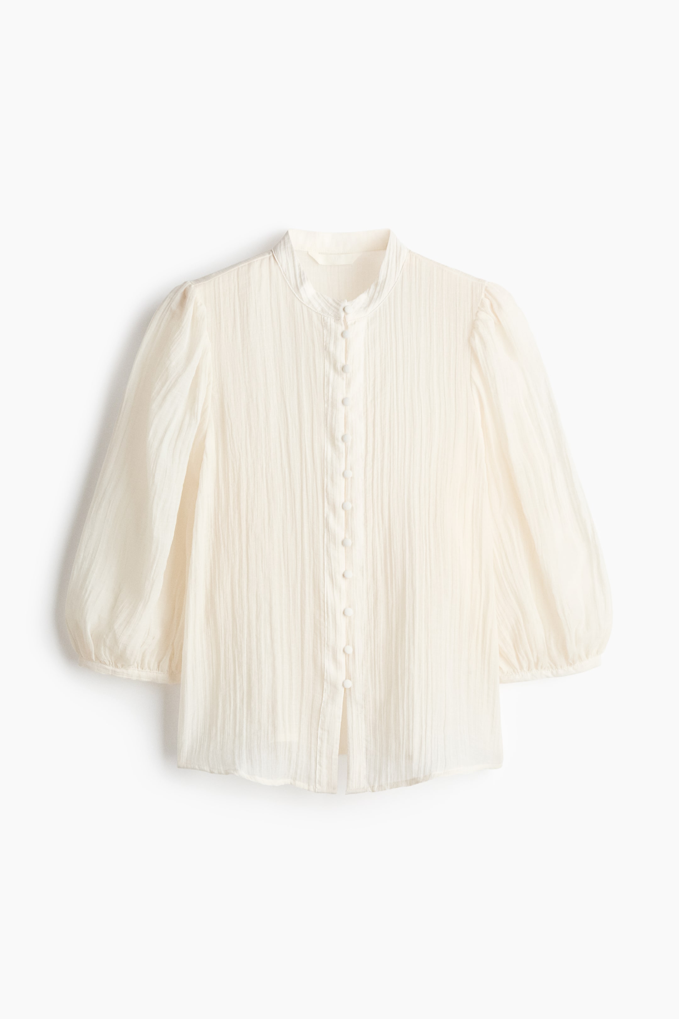 View larger image: This cream blouse showcases a front view, highlighting a crinkled texture all over. It is crafted with a band collar, a full front placket of small, round, cream buttons, and three-quarter length puffed sleeves with elasticized cuffs.